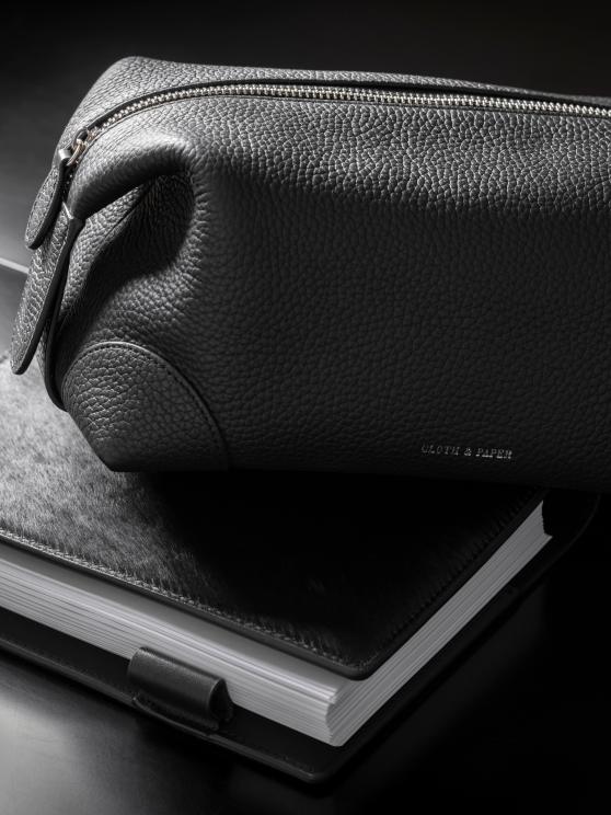 A black textured nylong pouch rests on top of a Ponyhair folio.