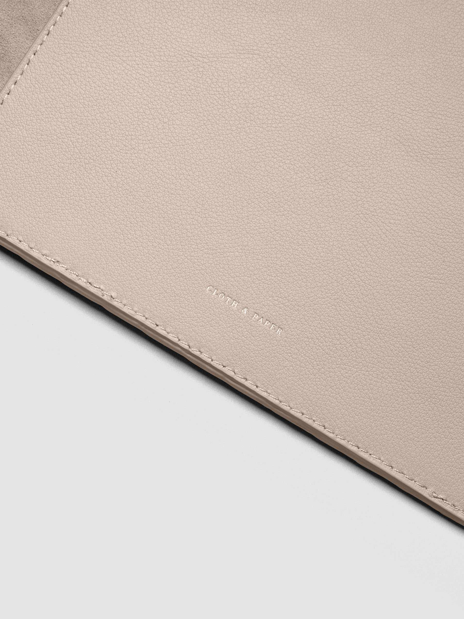 Close up of the foil Cloth & paper logo on the interior of a beige leather planner folio cover.