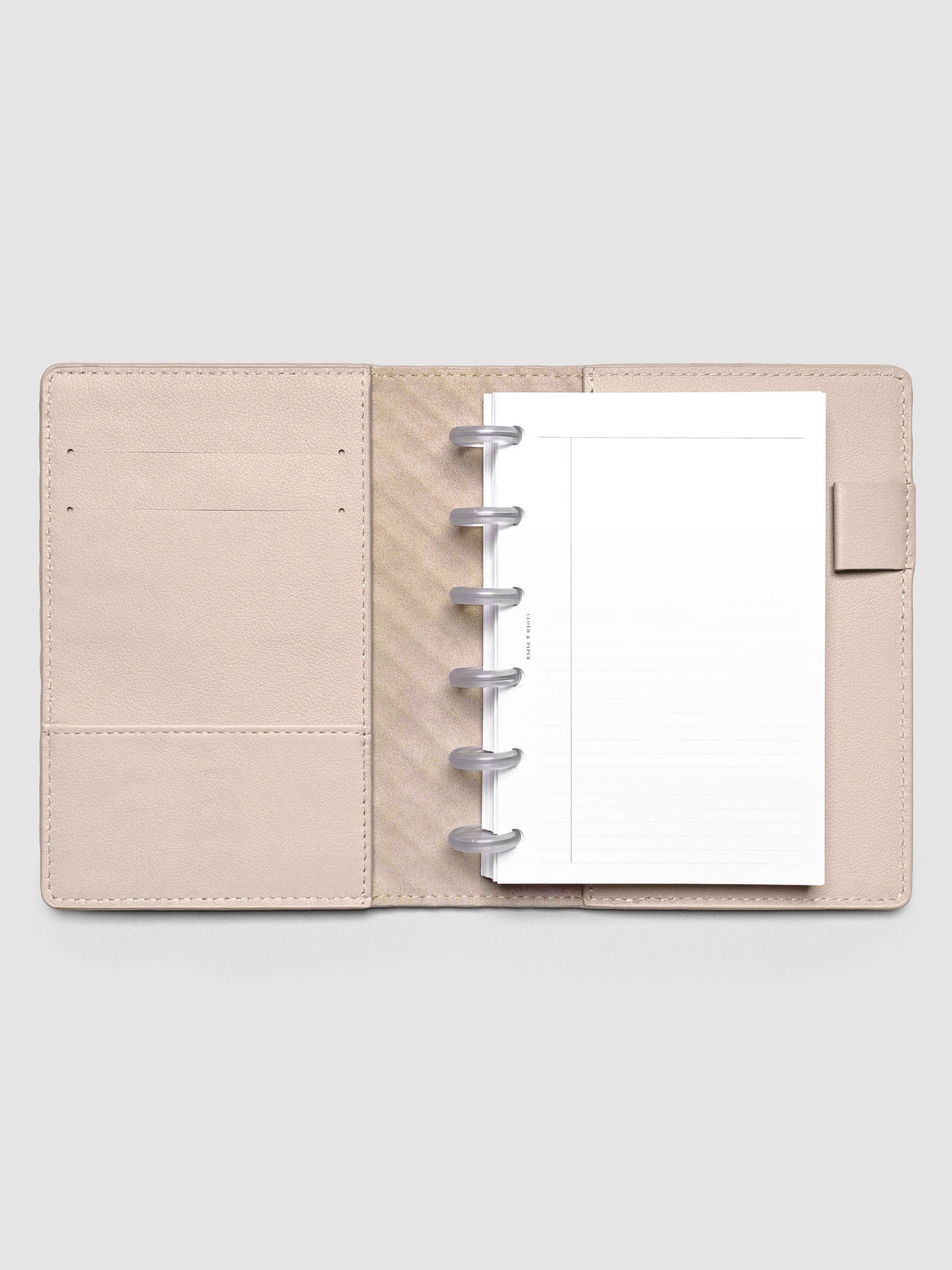 Open beige leather planner folio with a CP petite discbound planner inside.