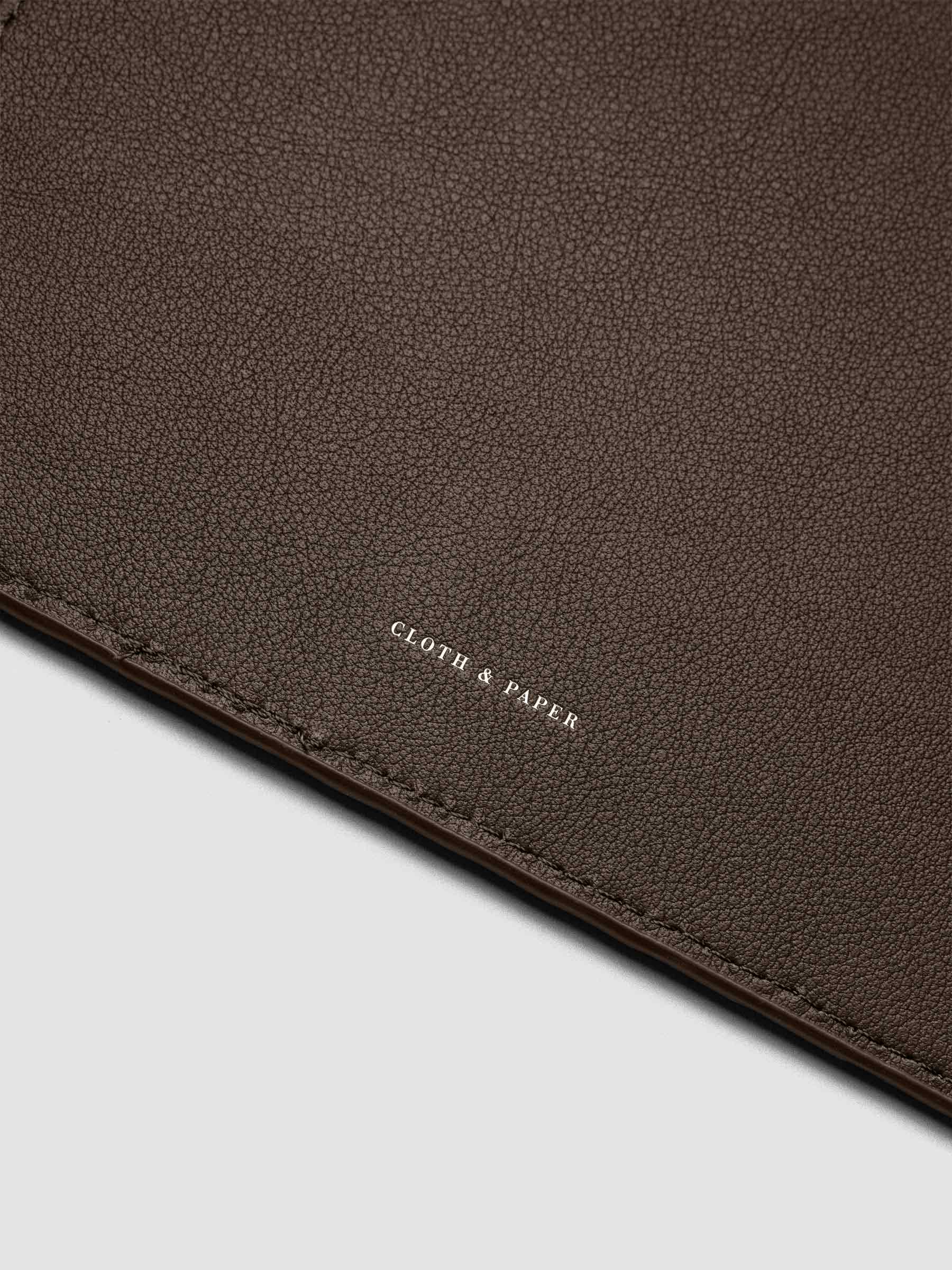 Close up of the foil Cloth & paper logo on the interior of a dark brown leather planner folio cover.