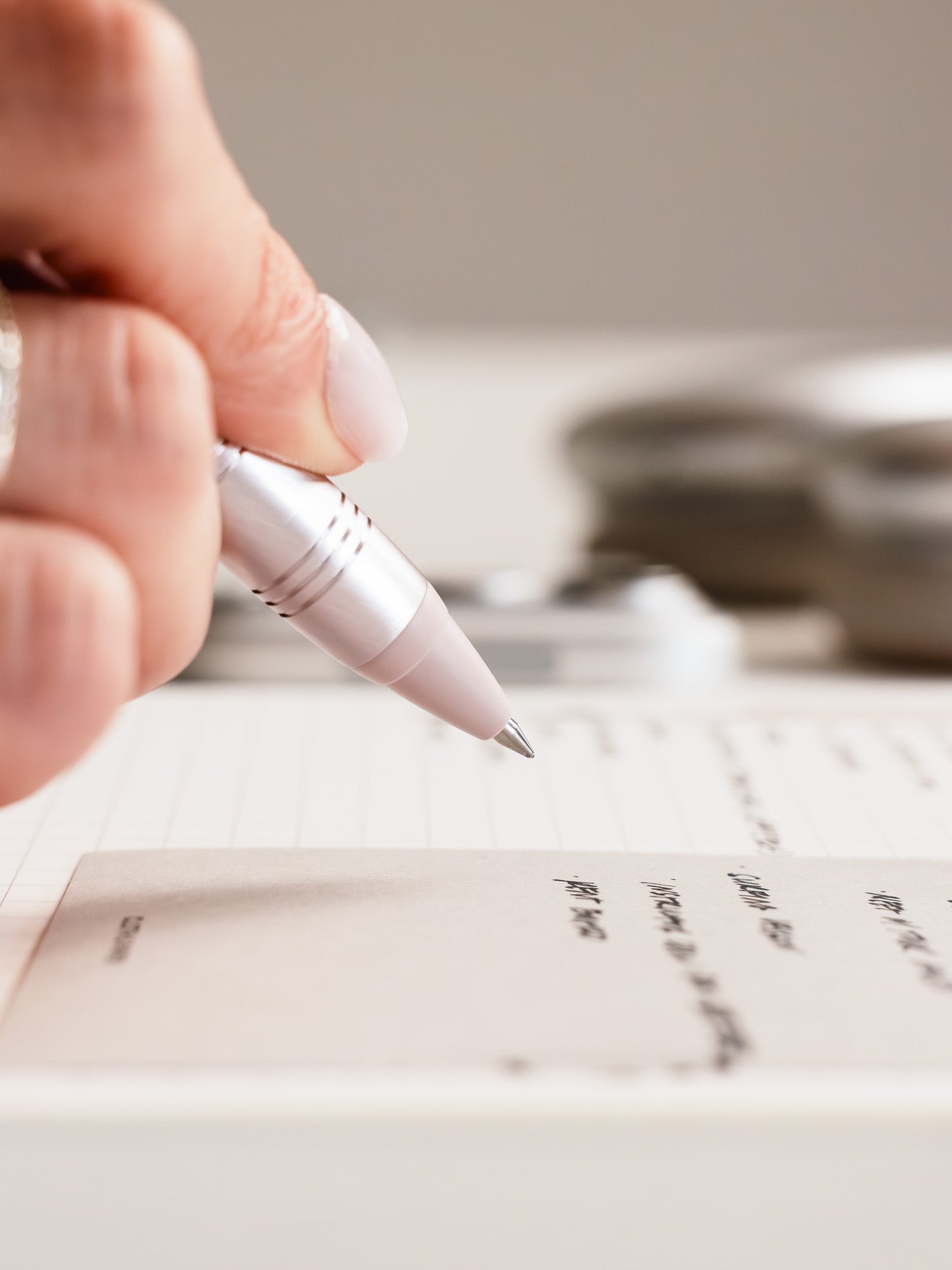 Woman writing in a notebook using the Uni-Ball Zento Flow Ballpoint Pen | Retreat Edition in the color Anthurium Pink with a 0.5 mm nib.