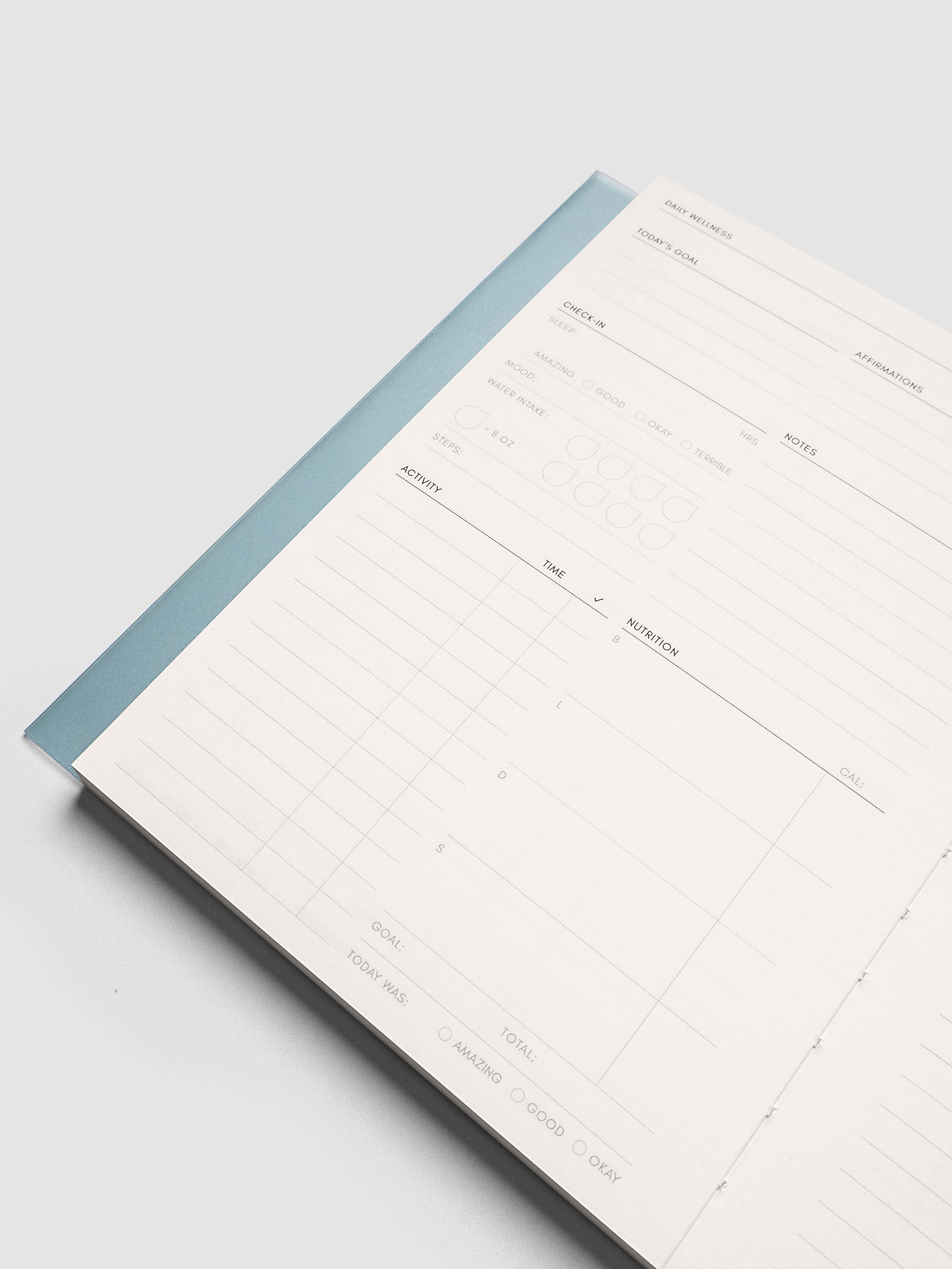 Close up of the Perfect Bound Notebook | A5 | Daily Wellness with a page lifted at an angle, light blue spine edge visible