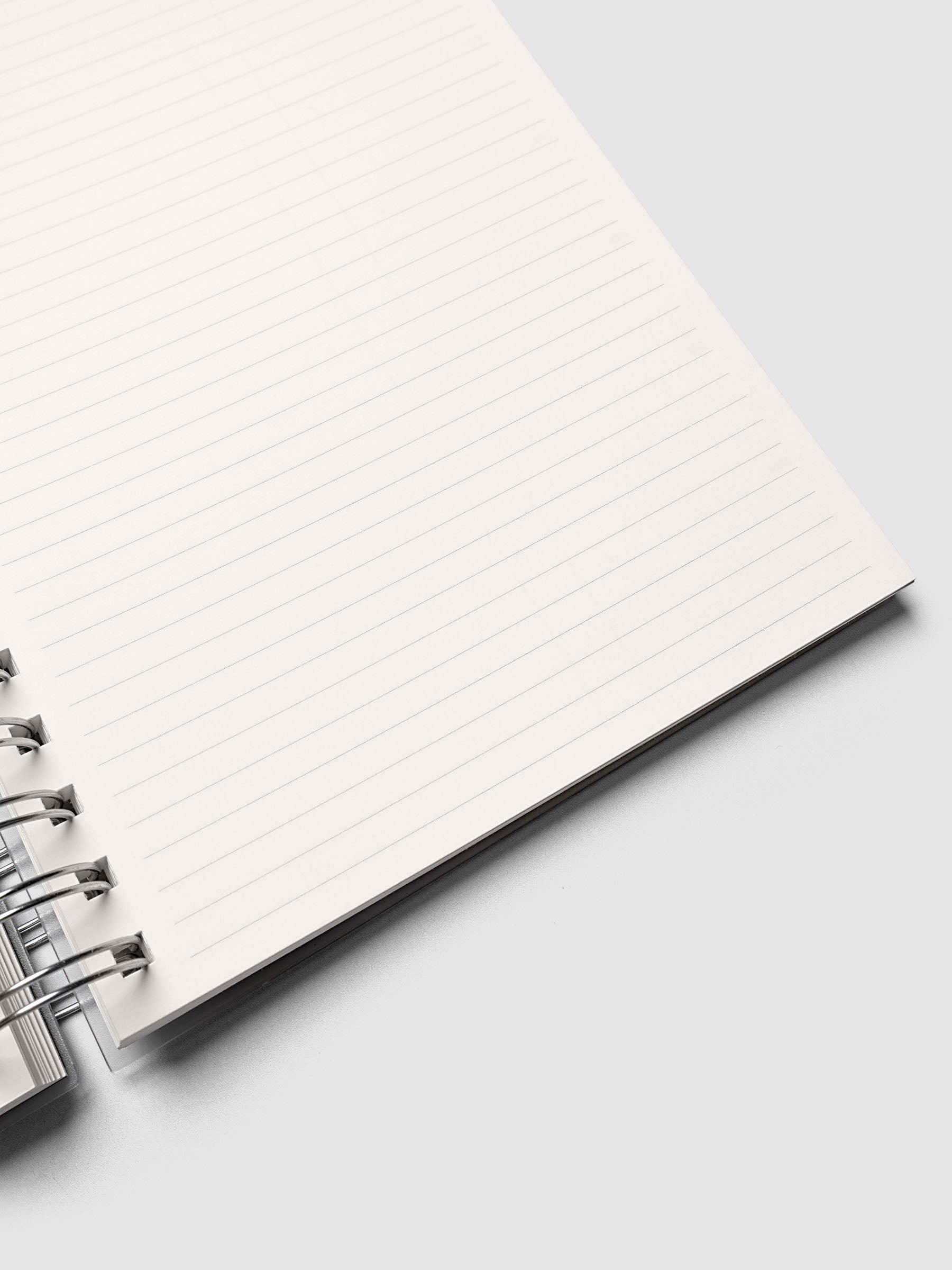 Close up of the Spiral Notebook | A5 | Weekly Checklist with a corner lifted, showing ruled lines and silver spiral binding