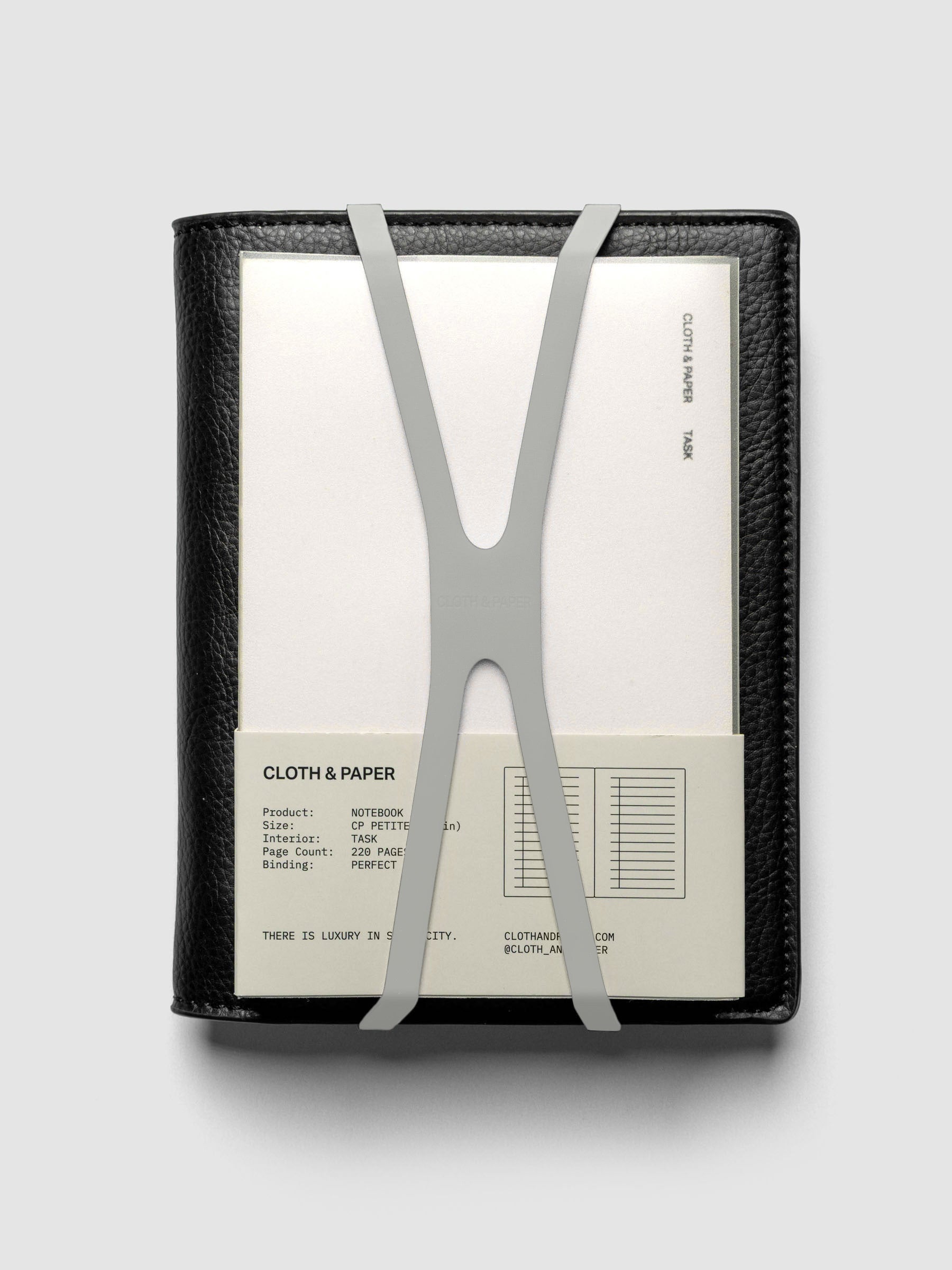 Small ash planner closure band holding a CP Petite perfect bound notebook on a black leather folio.