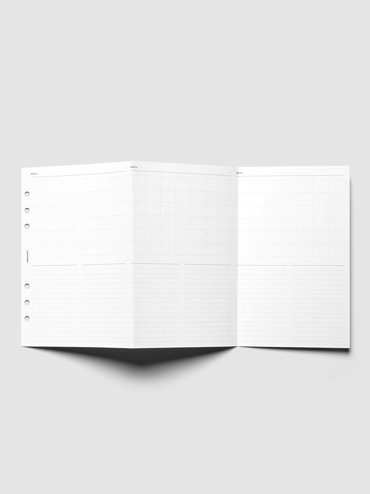 Monthly Fold Out Planner Insert Set of 2, A5 6-Ring Punch, the insert unfolded and standing on a pale gray surface, three monthly grid panels each sitting above lined note columns