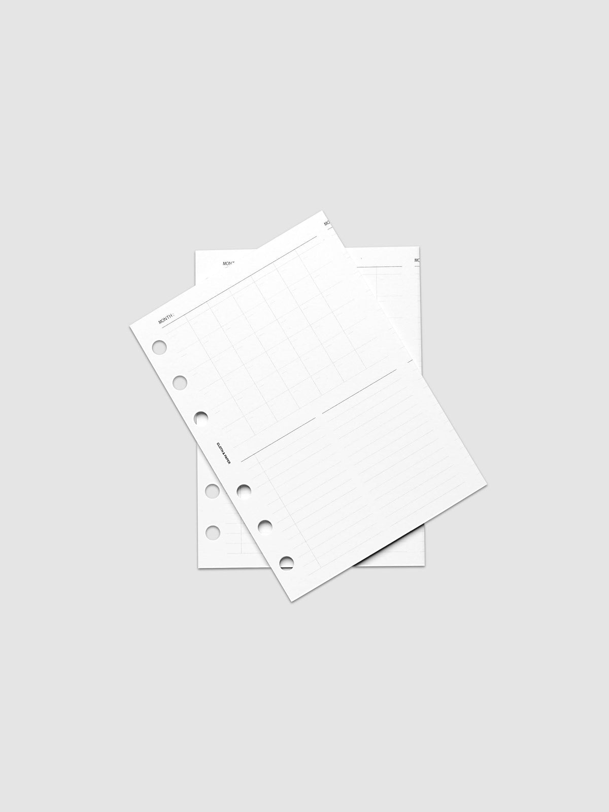 Monthly Fold Out Planner Insert Set of 2, A6 6-Ring Punch, both white inserts fanned over one another on a pale gray surface, round punch holes and gray grid printing visible