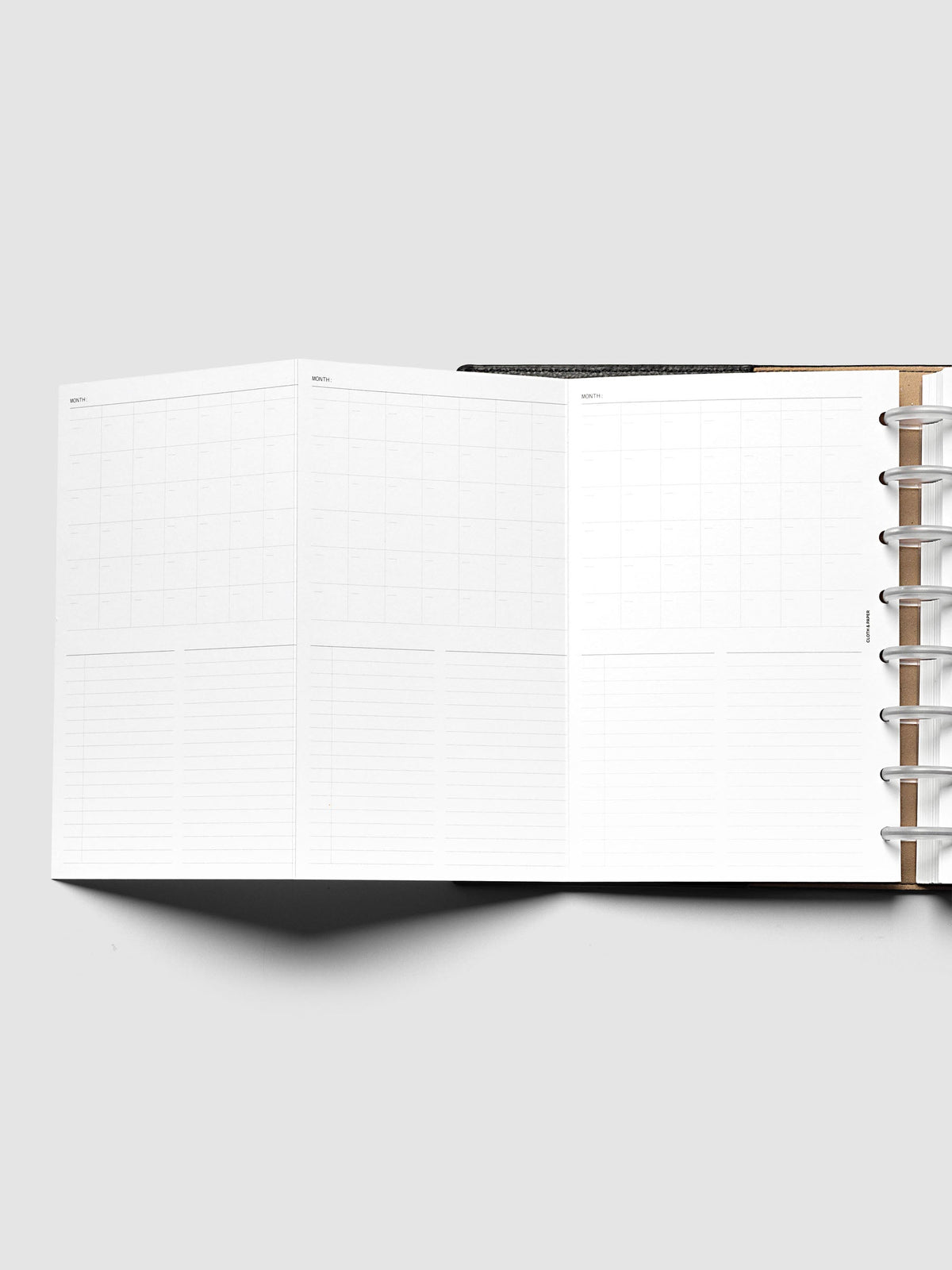 Monthly Fold Out Planner Insert Set of 2, Half Letter 8-Disc Punch, the insert opened out to the left of a black discbound planner, frosted clear discs and kraft cover at the right of the frame