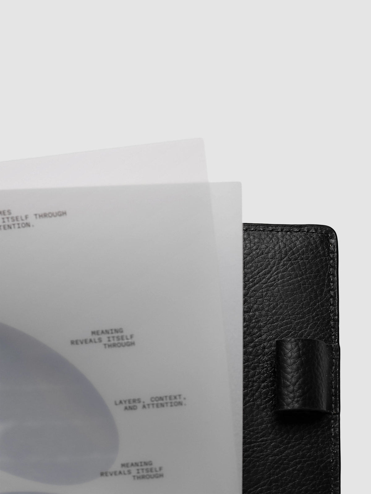 Nuanced Dashboard Trio, Half Letter 8-Disc Punch, top corner of two lifted translucent sheets against the black leather cover and its pen loop