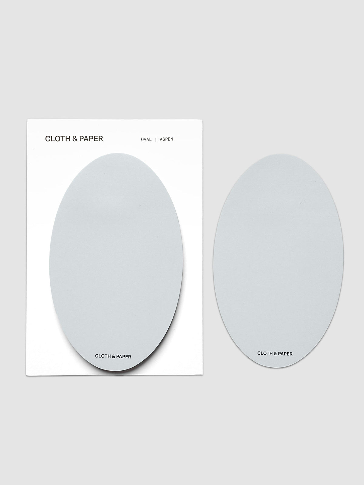 Oval Sticky Notes | Aspen with the pad on its white backing card beside a single loose oval sheet, both in the same soft pale blue gray, on a light gray background