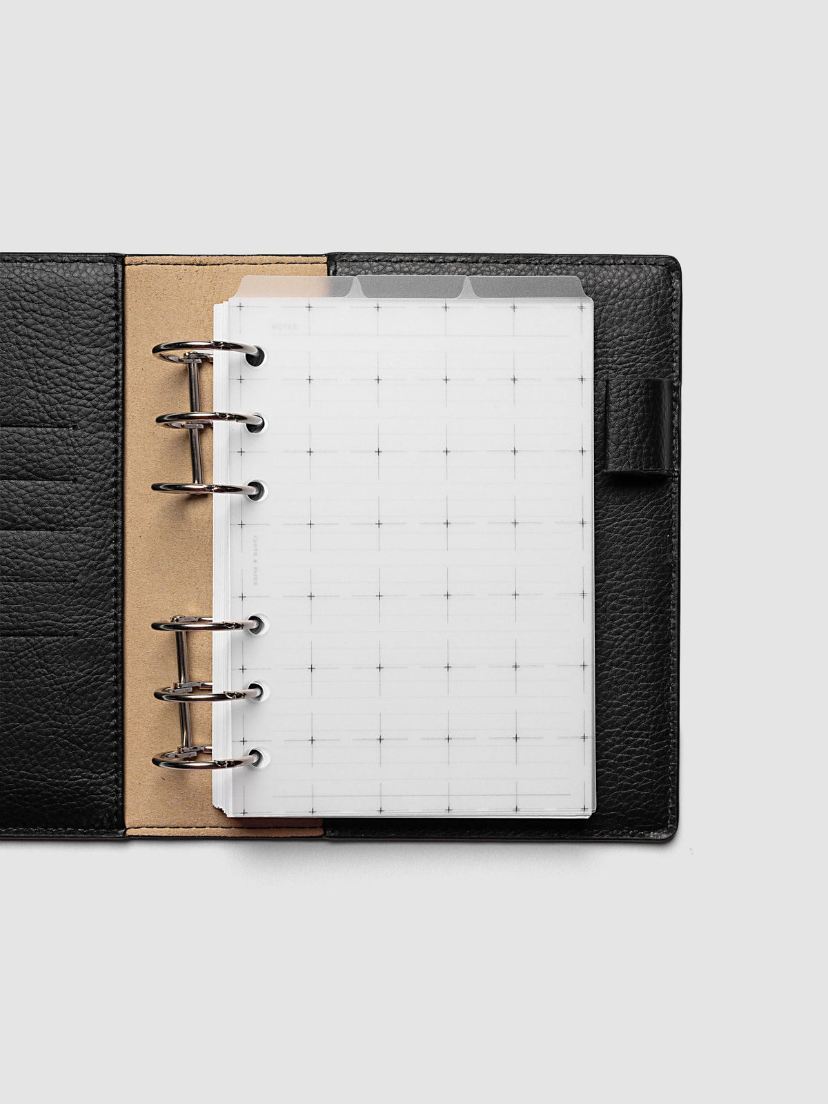 Grid Top Tab Dividers | Ultra-Thin, A6 6-Ring Punch, dividers inside an open black leather ring bound planner with silver rings and a tan suede interior, three tabs staggered at the top