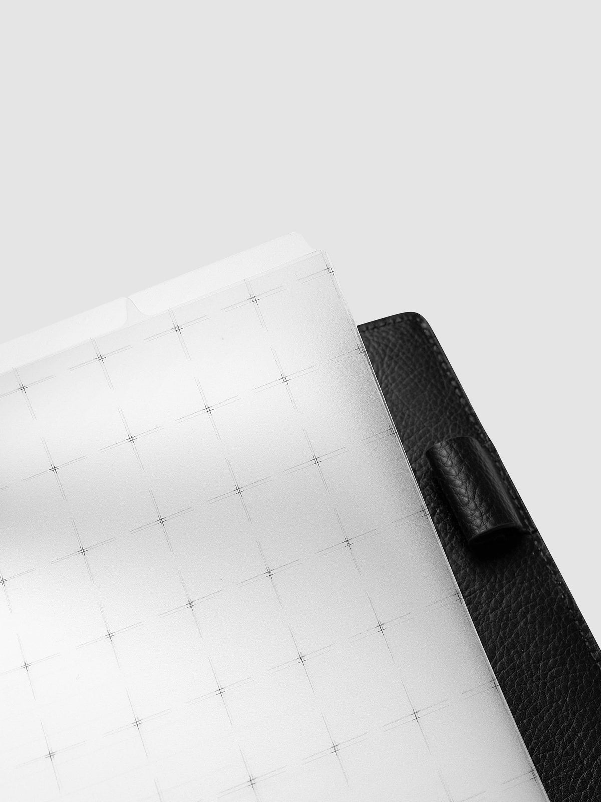 Grid Top Tab Dividers | Ultra-Thin, Half Letter 8-Disc Punch, angled close-up of the top corner and tab lifting away from a black leather cover with a leather pen loop