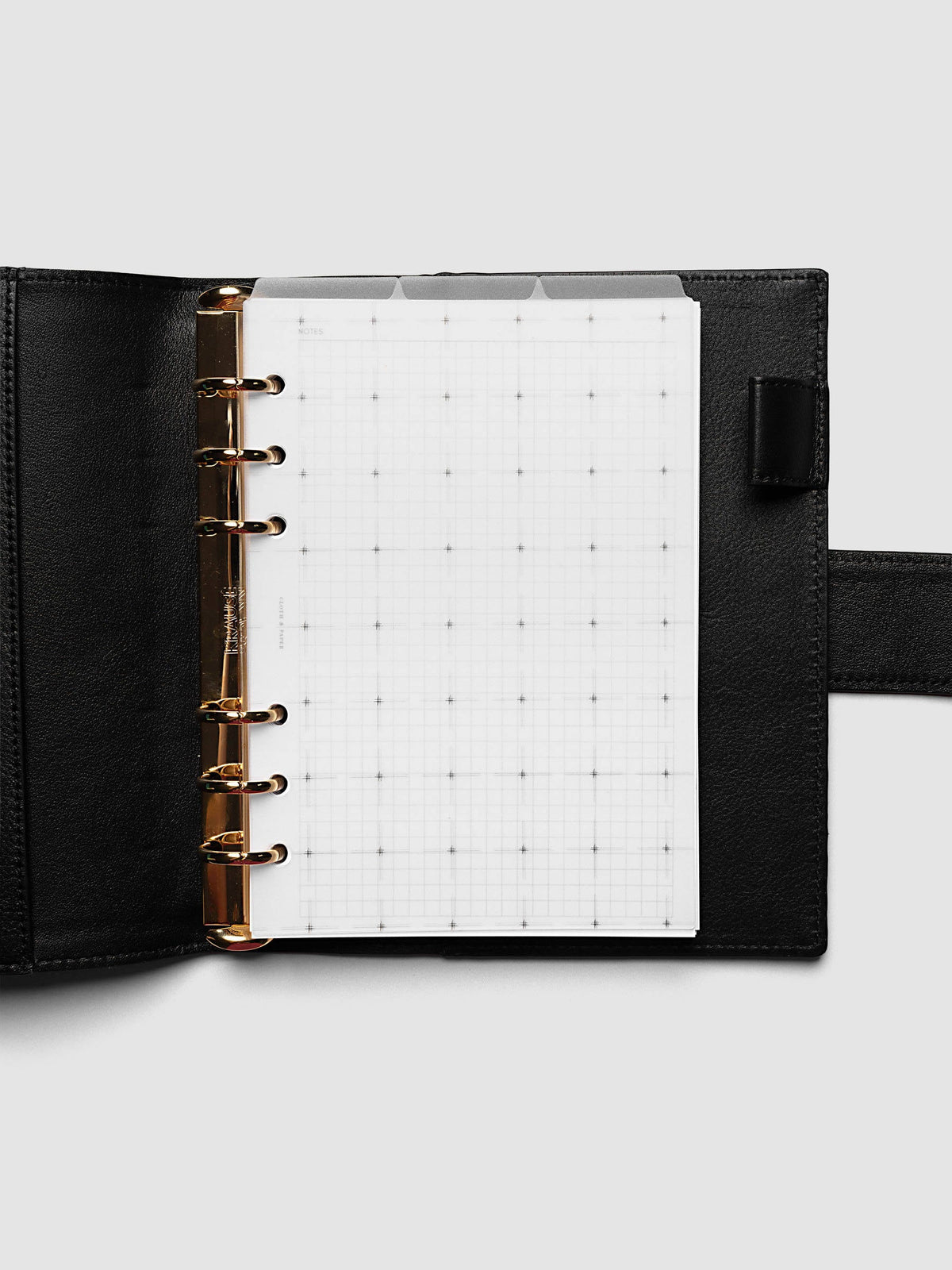 Grid Top Tab Dividers | Ultra-Thin, Personal Wide 6-Ring Punch, dividers in an open black leather ring bound planner with gold rings, three tabs staggered above a grid notes page