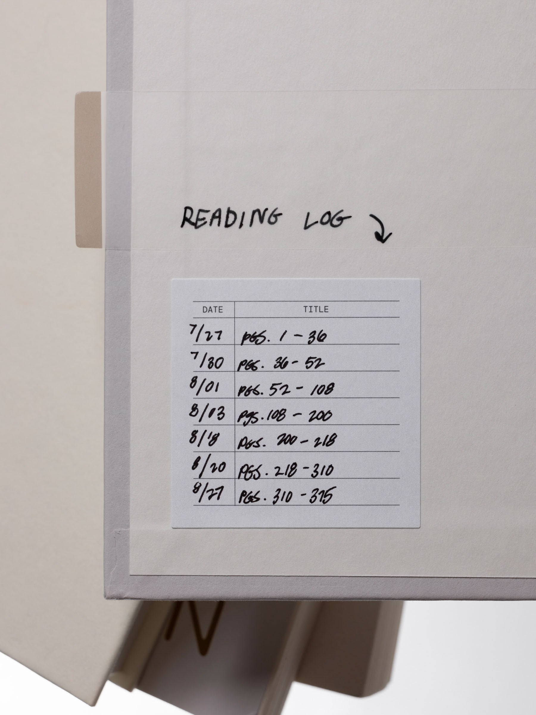Square, grey reading log label affixed to the inside cover of a book with handwritten notes.