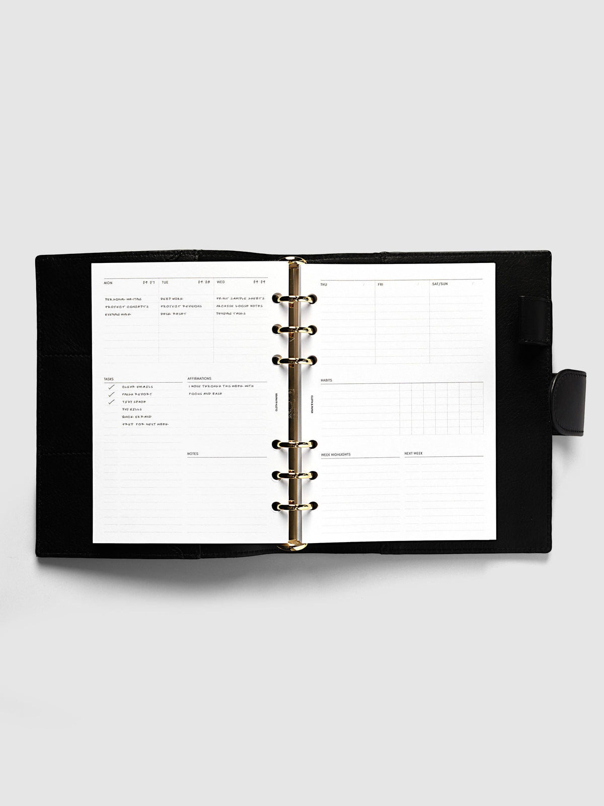 Weekly Essentials Planner Inserts, Personal Wide 6-Ring Punch, weekly spread open on the rings of a black leather planner