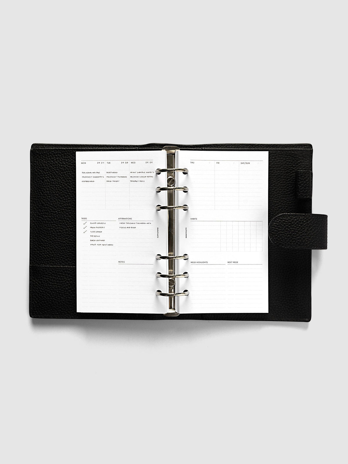 Weekly Essentials Planner Inserts, Personal 6-Ring Punch, weekly spread open on the rings of a black leather planner