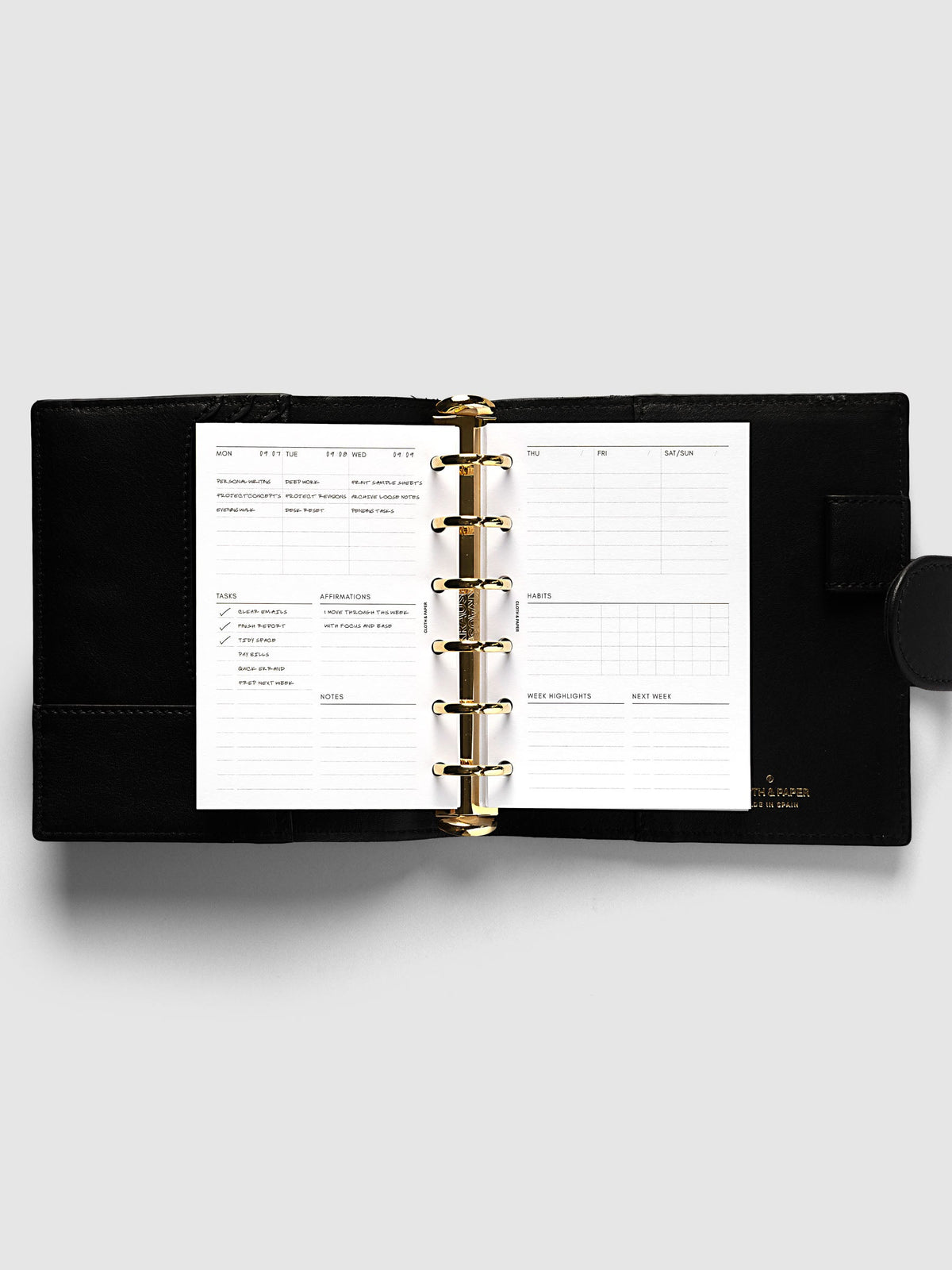 Weekly Essentials Planner Inserts, Pocket 6-Ring Punch, weekly spread open on the rings of a black leather planner