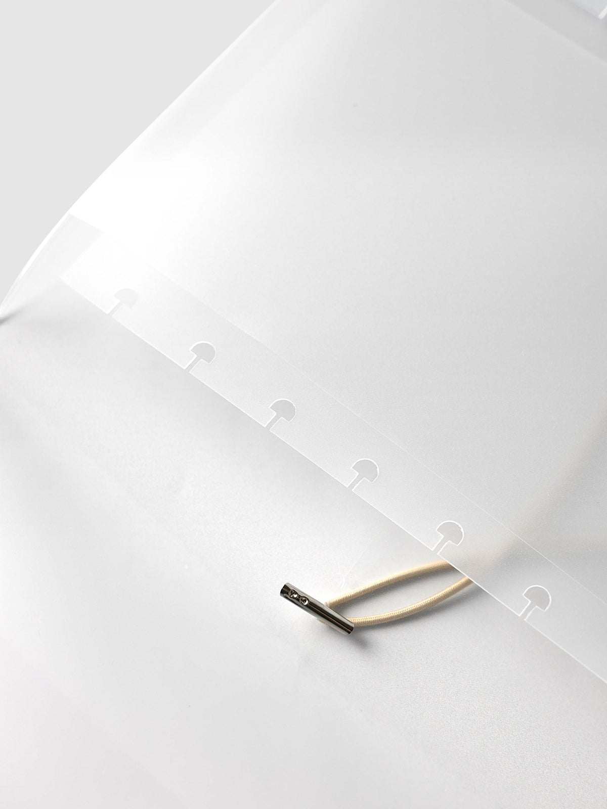 Close-up of the punched disc strip and beige bungee cord with its silver metal end inside the frosted vinyl Folio Cover