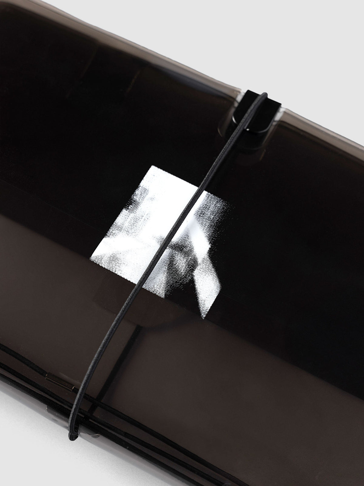 Close-up of the white halftone photo print on the front of the tinted black vinyl Image Duo Travel Cover, under the black elastic closure and black clip