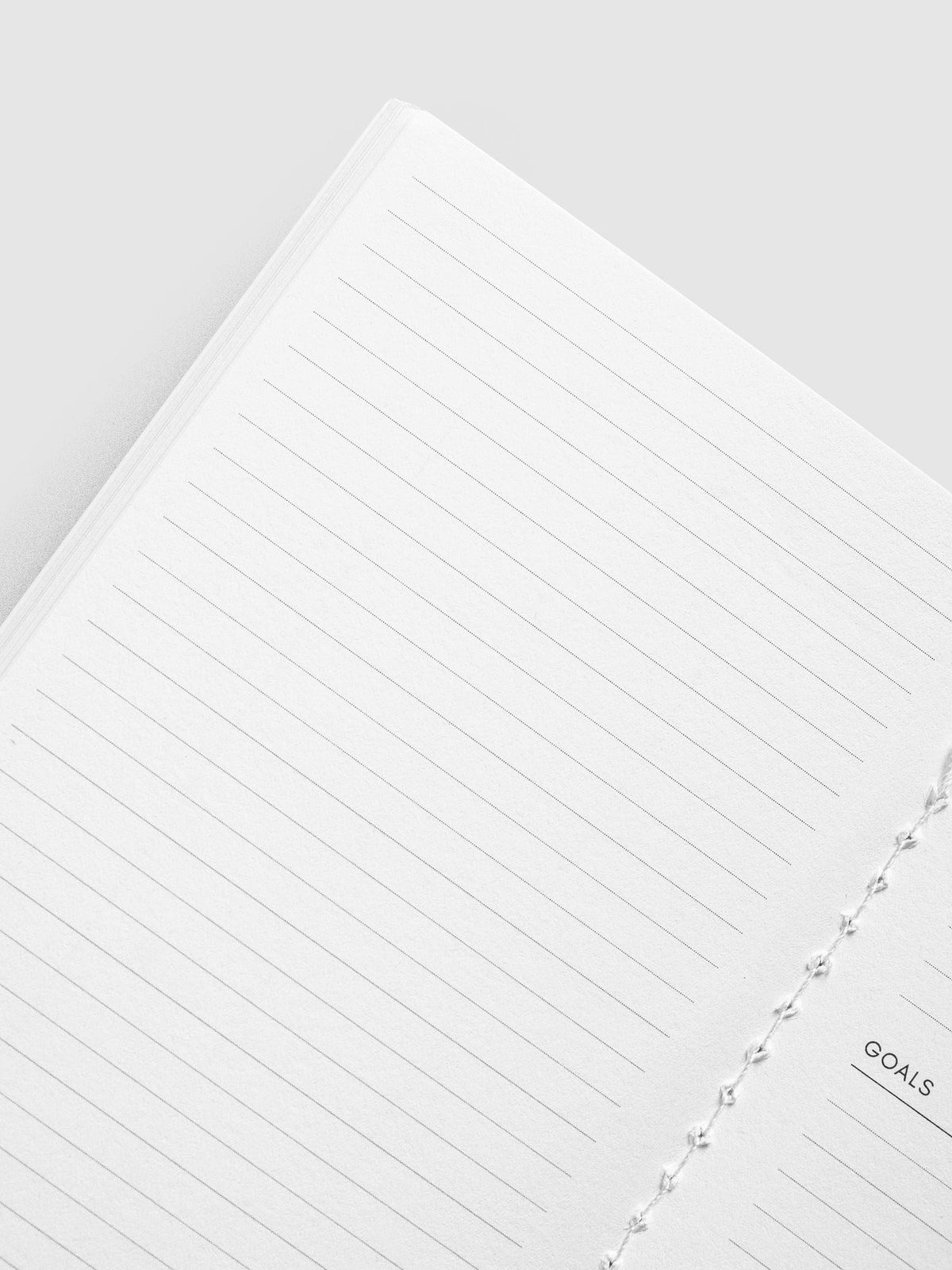Angled close-up of the lined page and white stitched binding in the Monthly Overview Pocket Plus