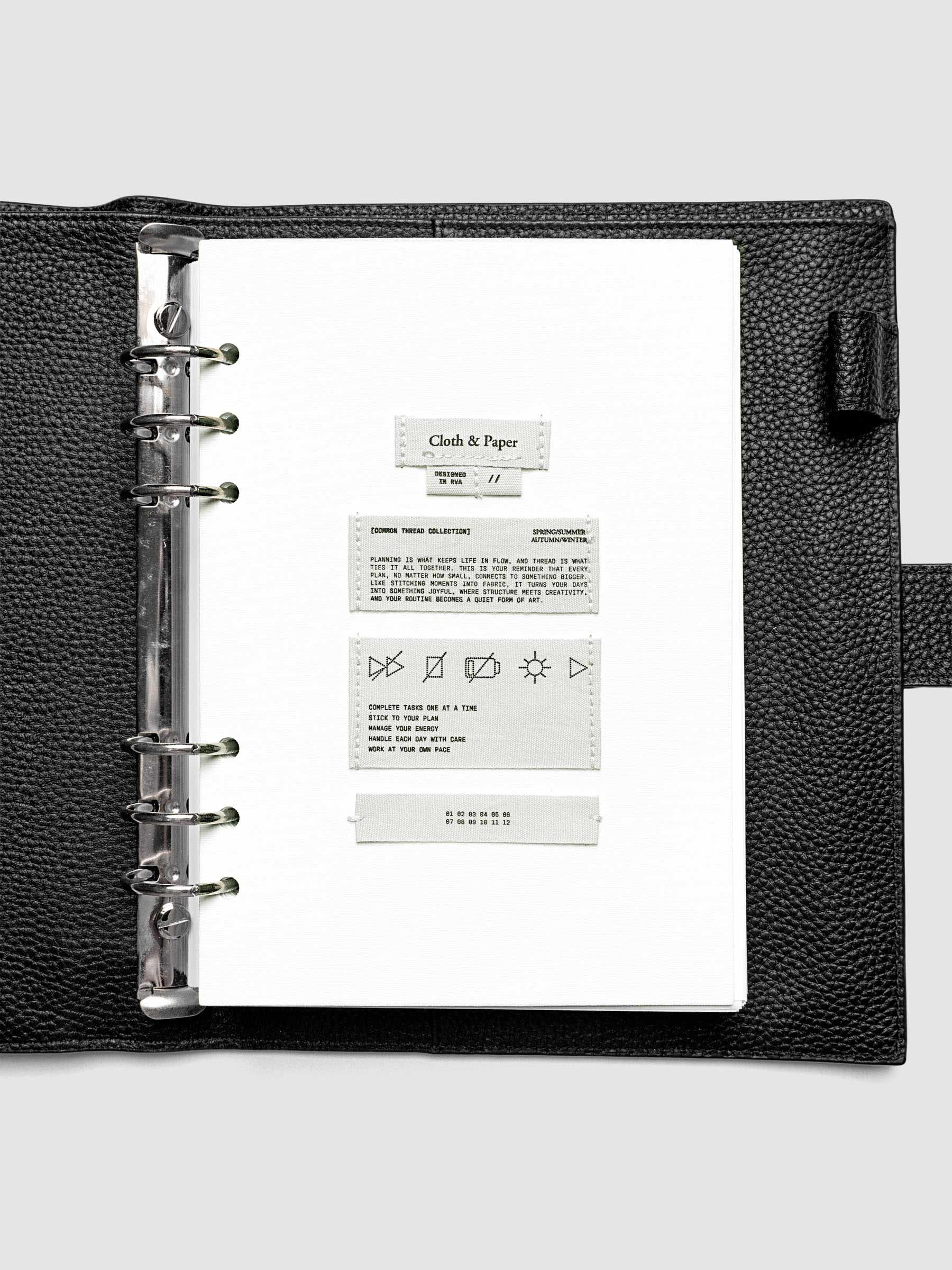 Sewn Tags Planner Dashboard pre-punched for 6-ring planners in size A5 shown in a black leather agenda.