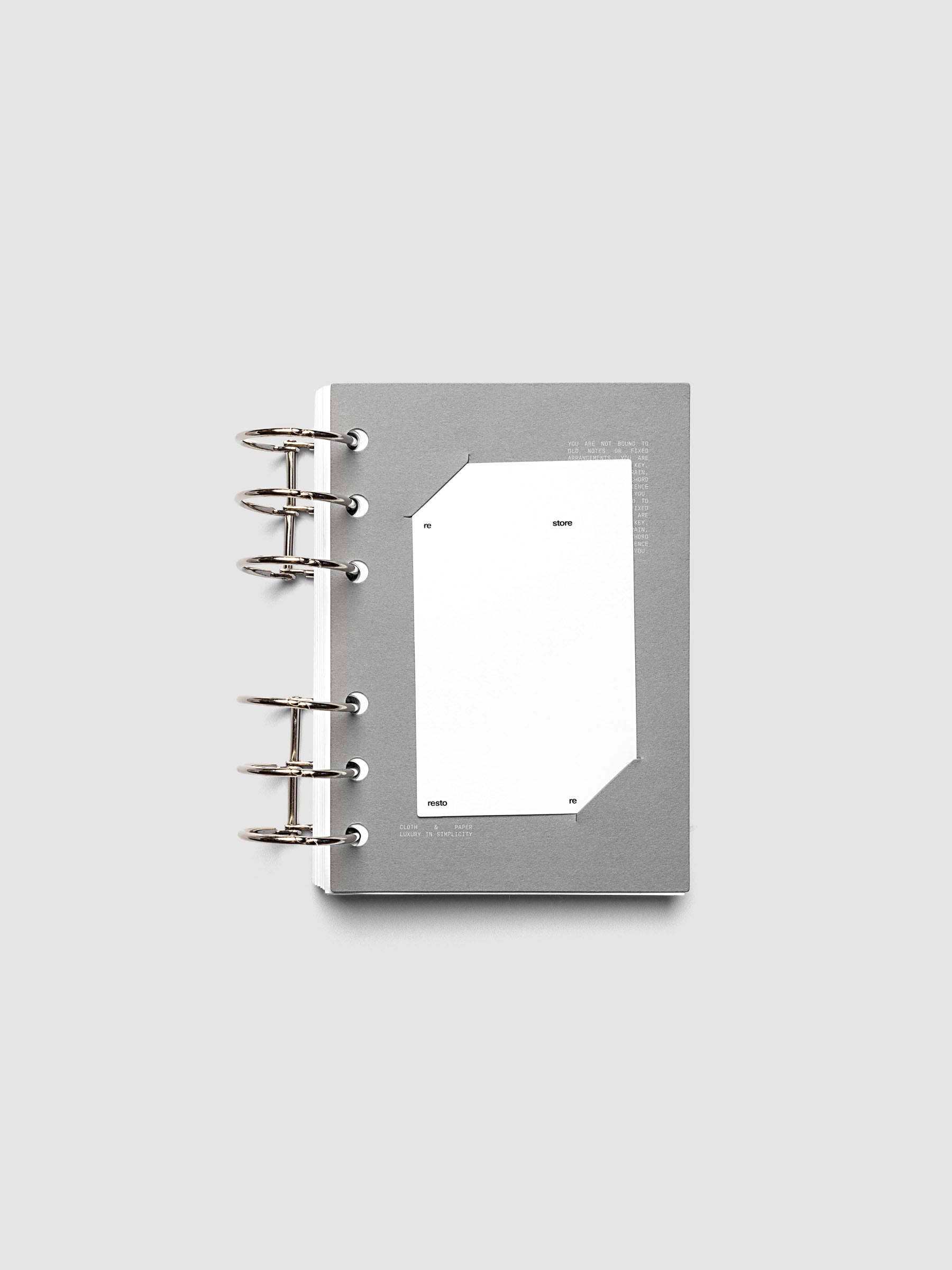 Grey cardstock planner dashboard with white plastic card inserted in slits with white printed text shown in size A6 shown in a ring bound planner.