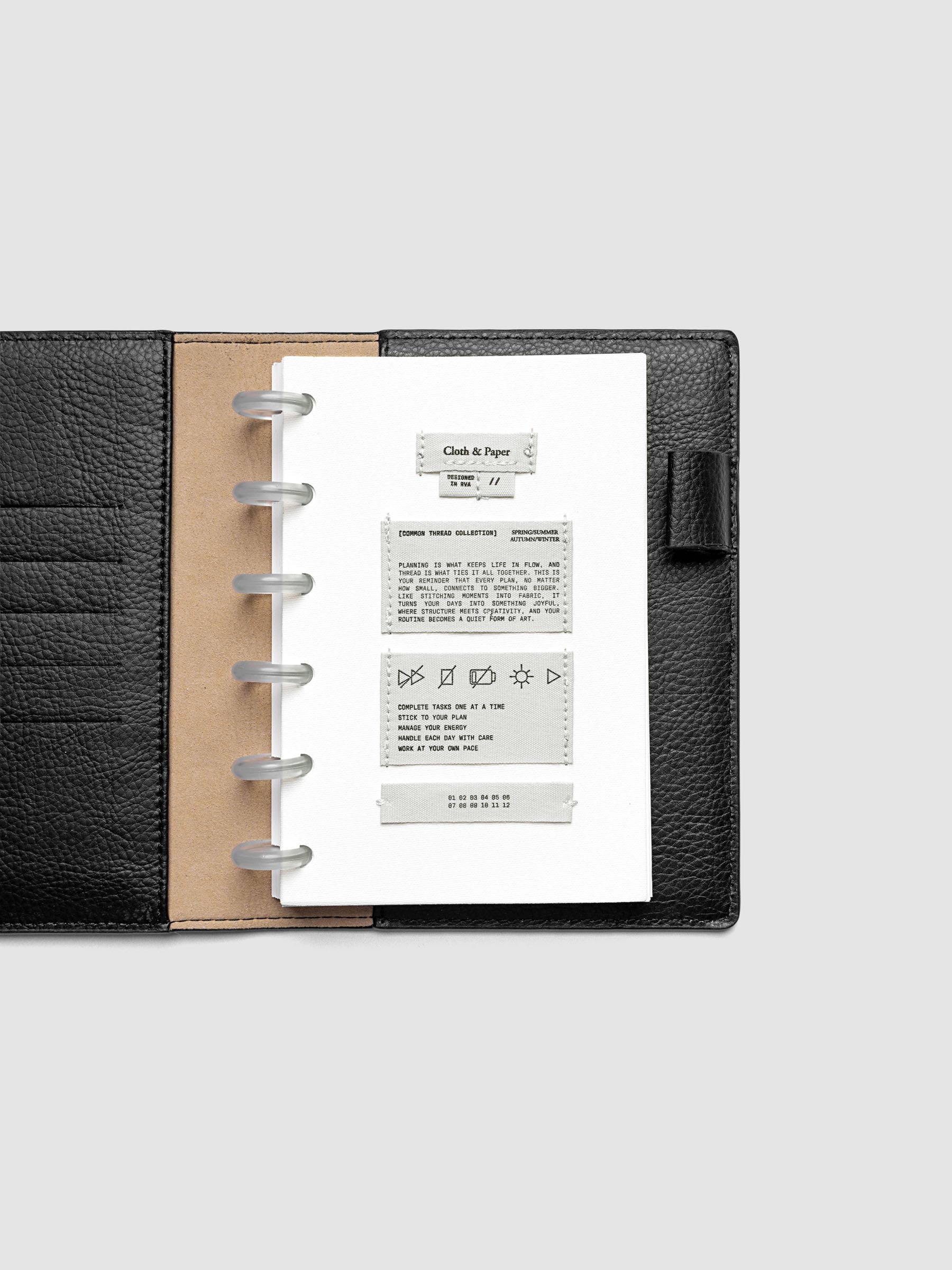 Sewn Tags Planner Dashboard pre-punched for discbound planners in size CP Petite shown in a black leather folio.