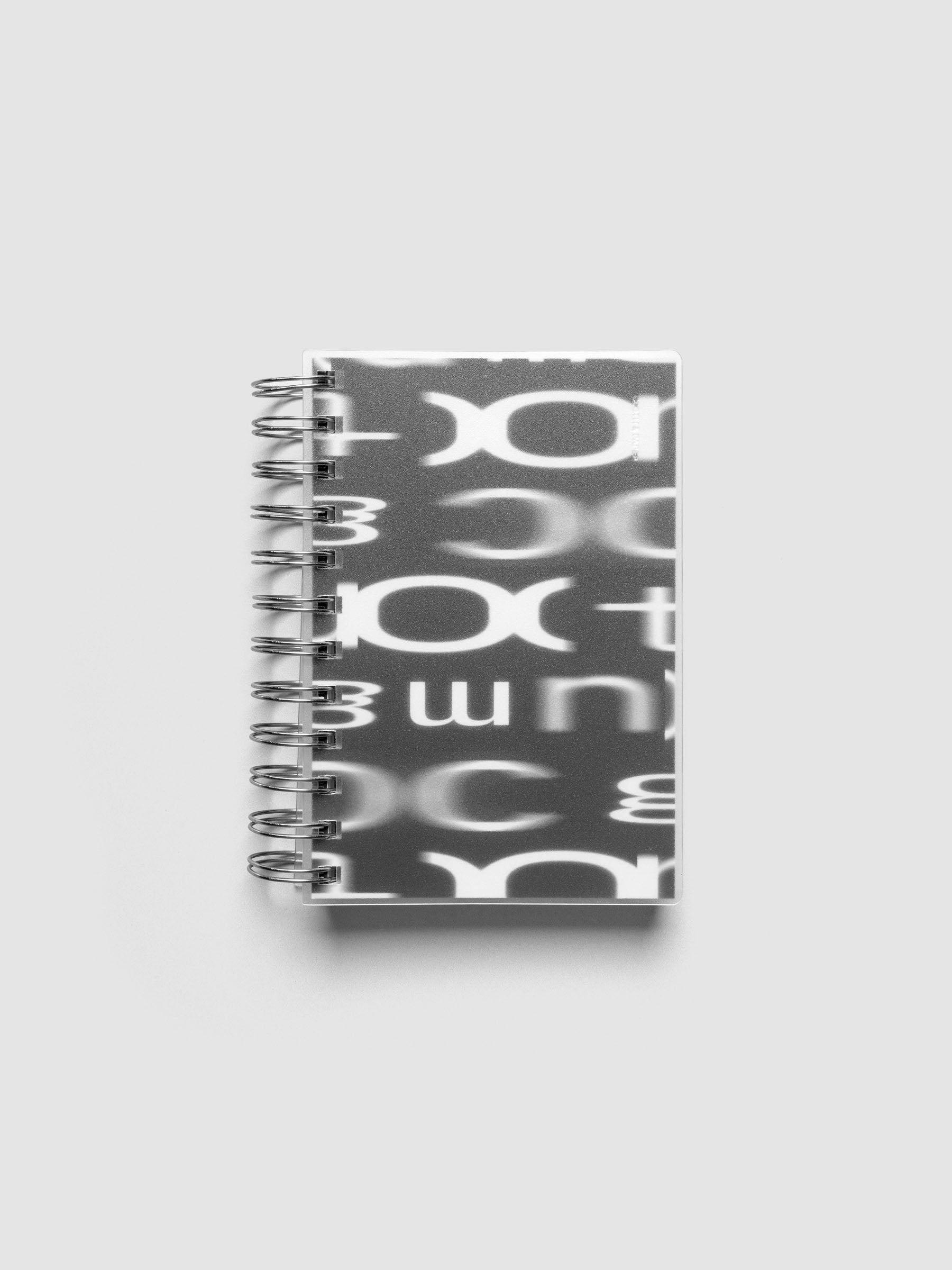 Spiral Notebook dashboard in the pattern Blurred Letters shown in size CP Petite inside a notebook with the frosted transparent cover overlayed.