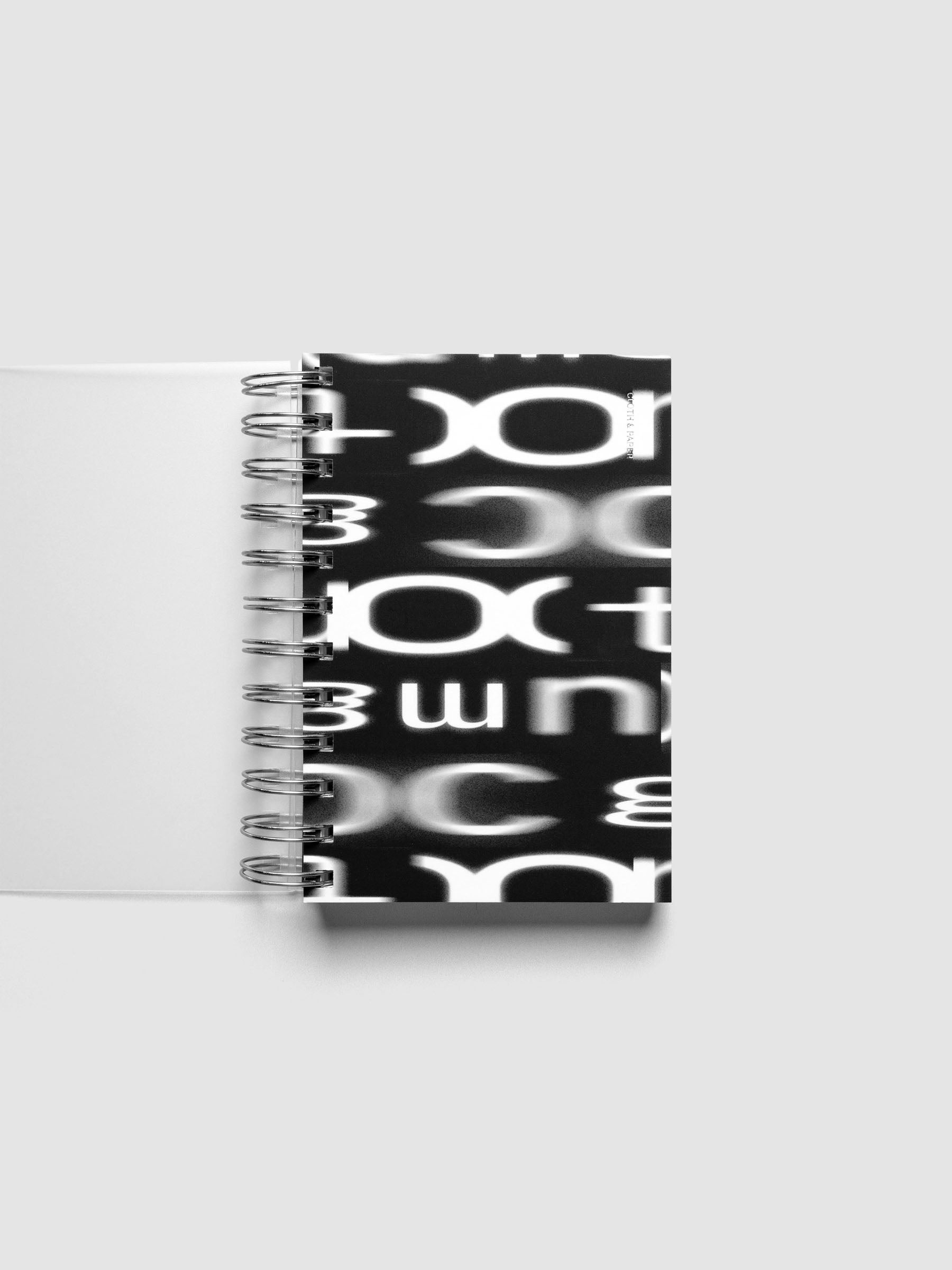 Spiral Notebook dashboard in the pattern Blurred Letters shown in size CP Petite inside a notebook.