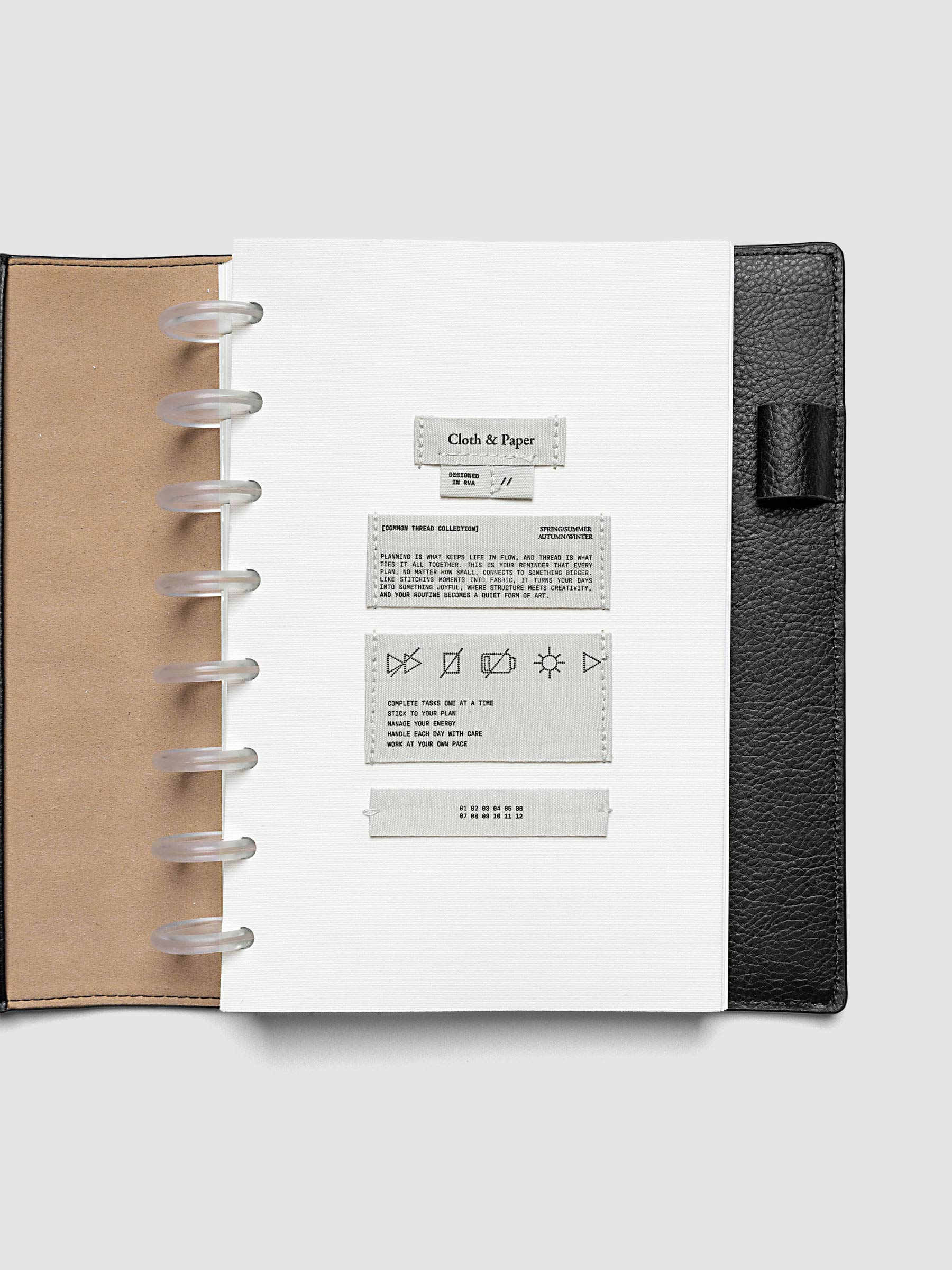 Sewn Tags Planner Dashboard pre-punched for discbound planners in size Half Letter shown in a black leather folio.