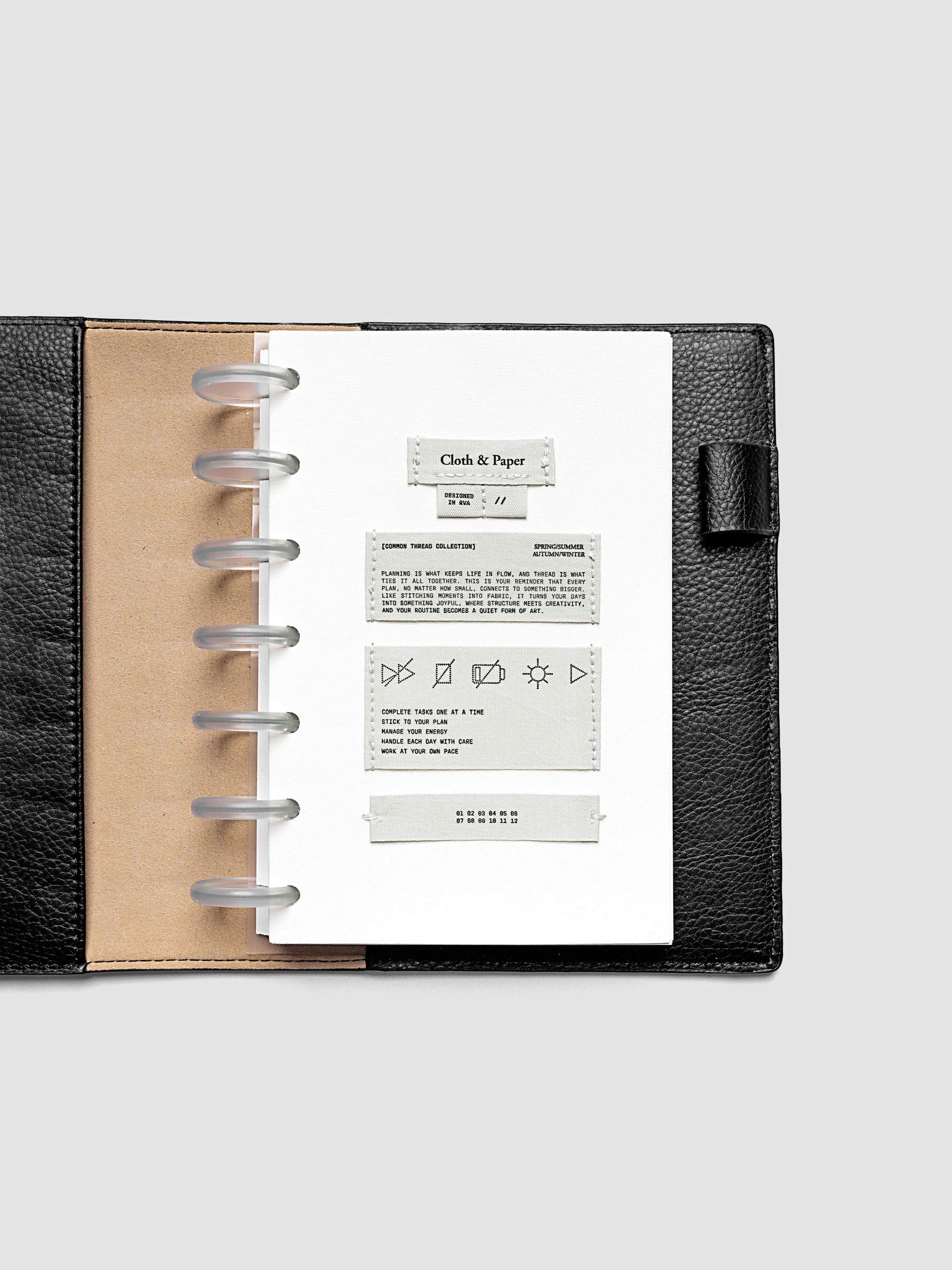Sewn Tags Planner Dashboard pre-punched for discbound planners in size HP Mini shown in a black leather folio.
