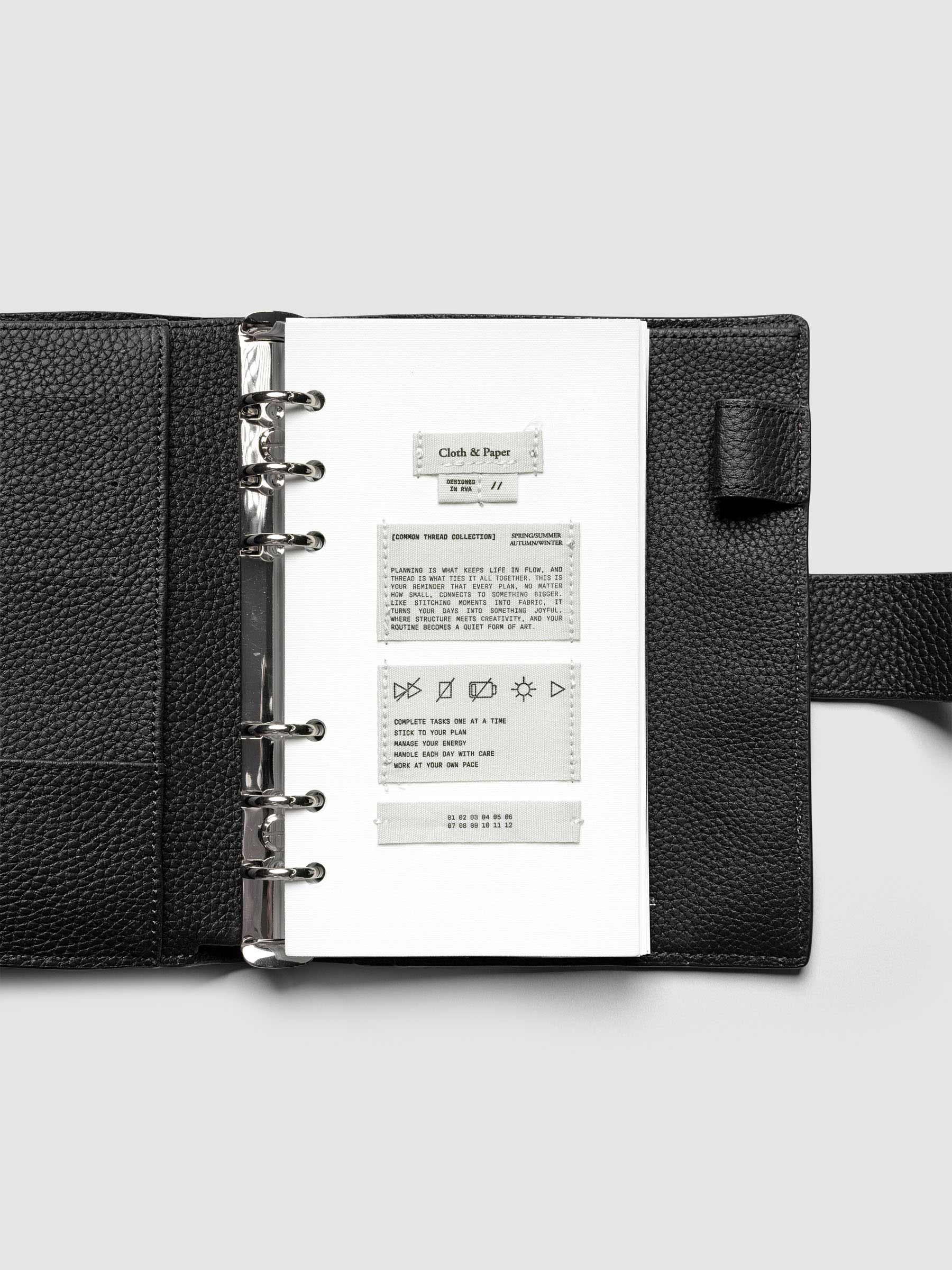Sewn Tags Planner Dashboard pre-punched for 6-ring planners in size Personal shown in a black leather agenda.
