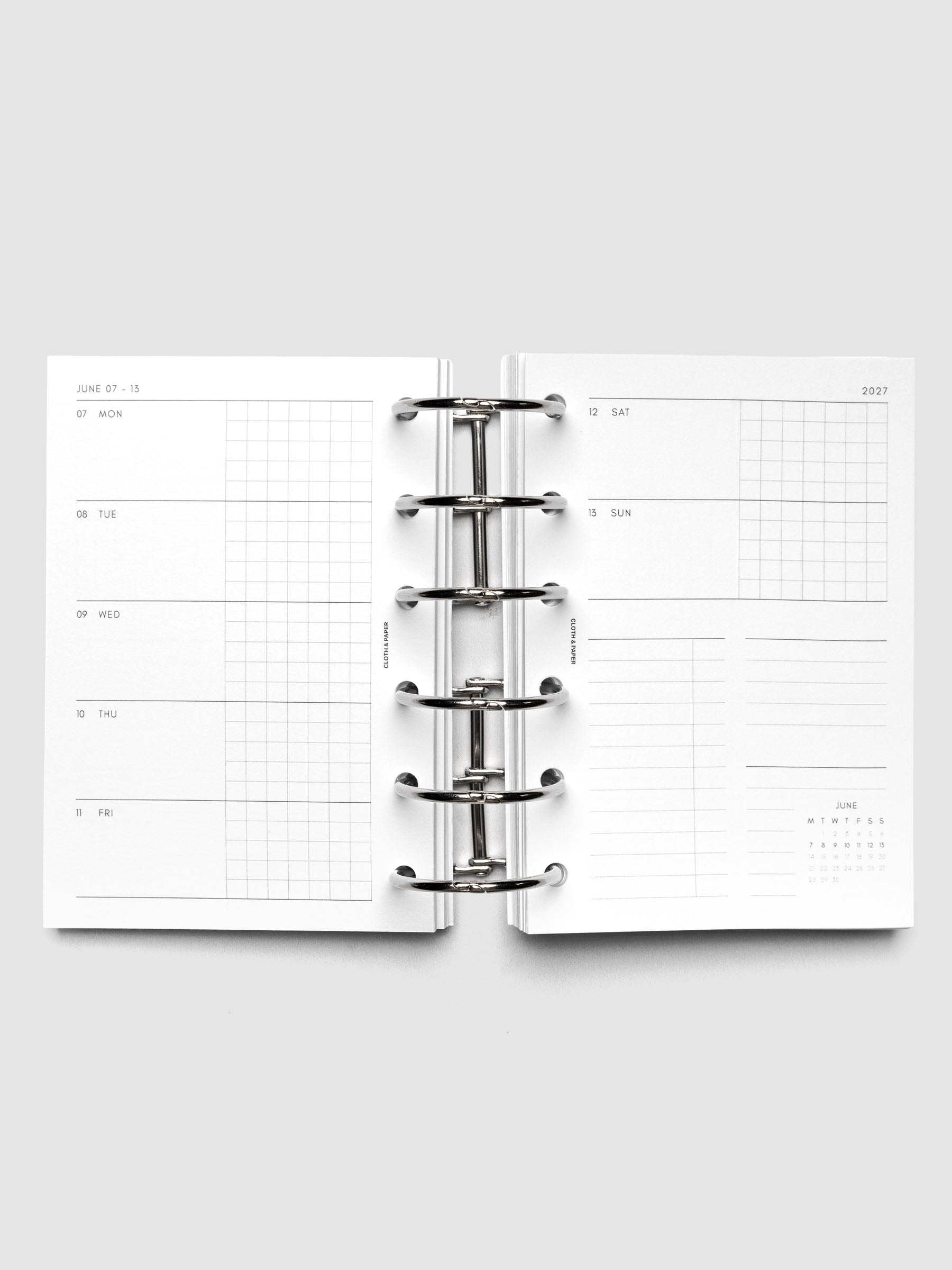 Open planner showing the full two-page 2027 Dated Weekly Horizontal Monday Start spread in Pocket 6-Ring Punch size, with split open and graph daily columns on the left and weekend dates, tasks, notes, and mini monthly calendar on the right