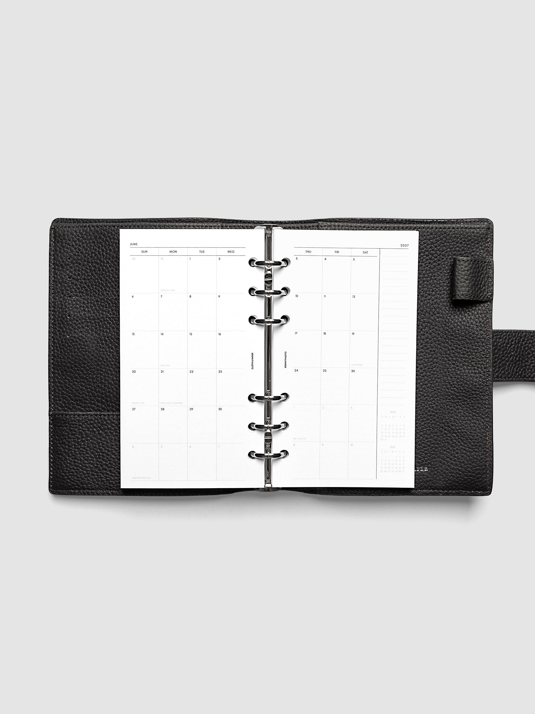 Open planner showing the full two-page 2027 Dated Monthly Sunday Start spread in Personal 6-Ring Punch size, with calendar grid, notes column, and mini calendars in the bottom right corner