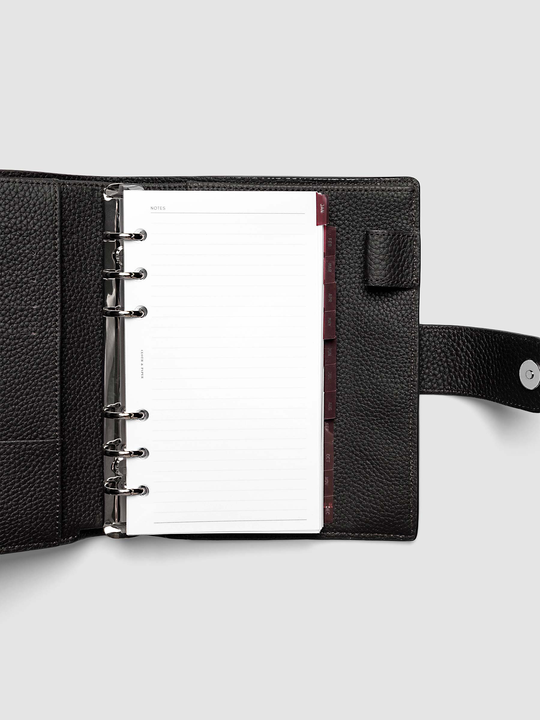 Personal 6-Ring Punch Ultra-Thin Monthly Dividers in deep red shown tabbed inside a planner