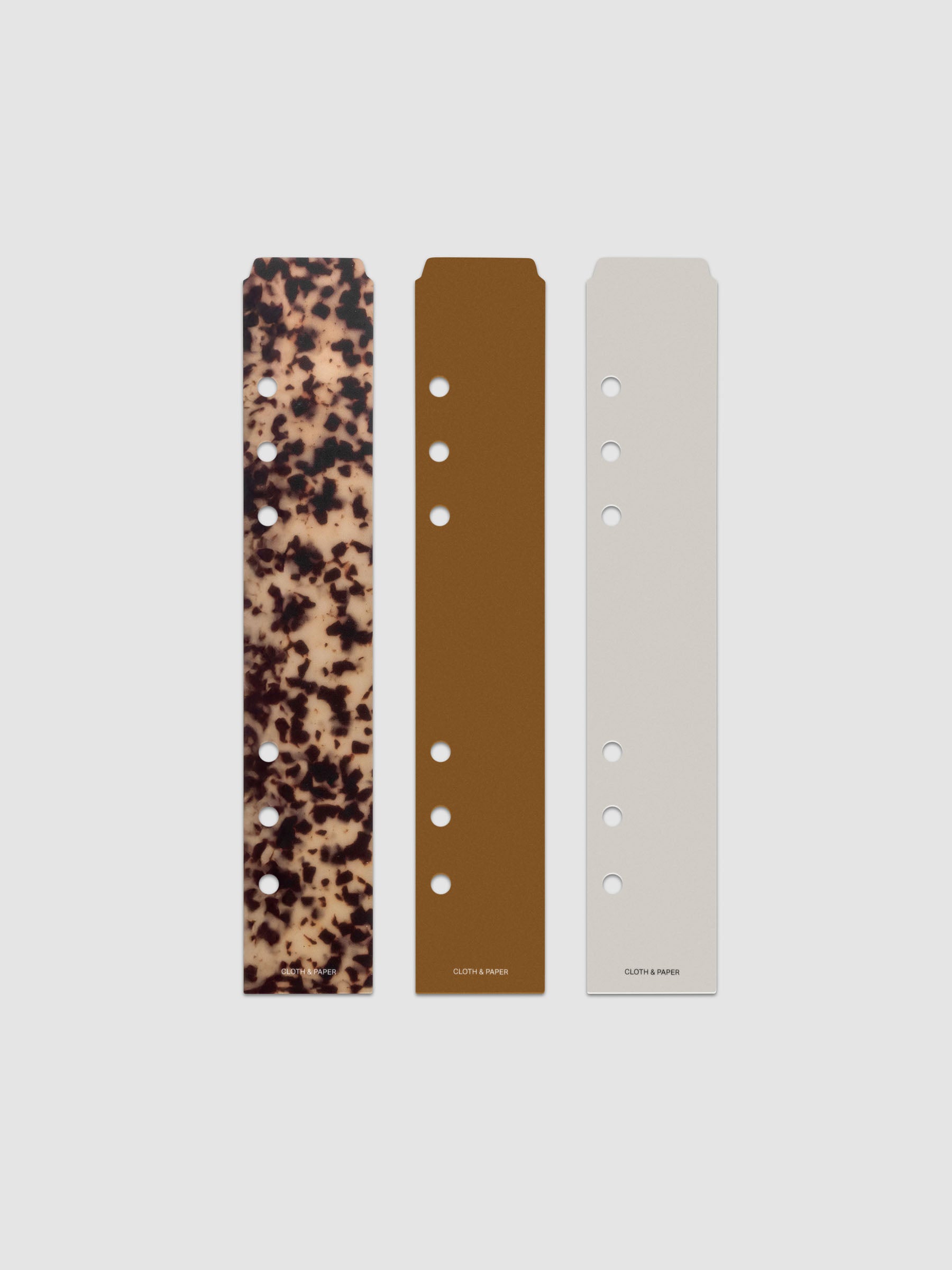 One of each color Narrow Page Marker in Vol. 2 shown hanging from string against a white fabric background.