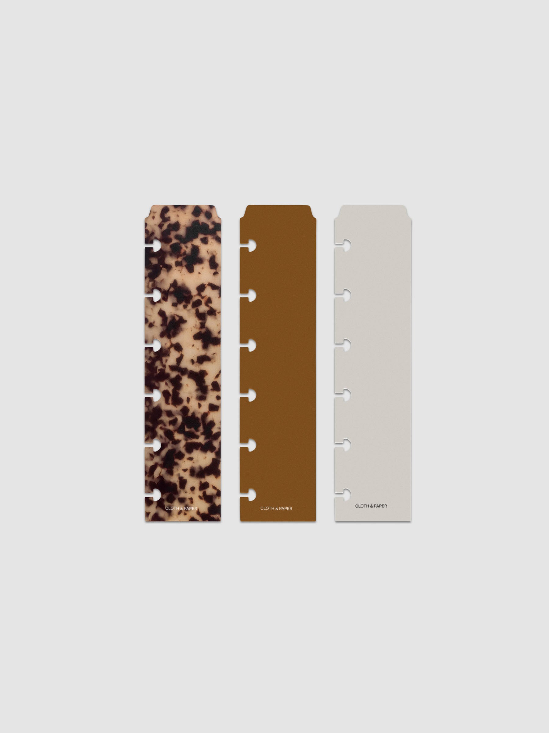 Narrow Page Marker Set Vol. 2, a set of 3 page markers for planners and notebooks shown in size CP Petite. Includes one tortoiseshell pattern, one solid brown, and one solid grey page marker.