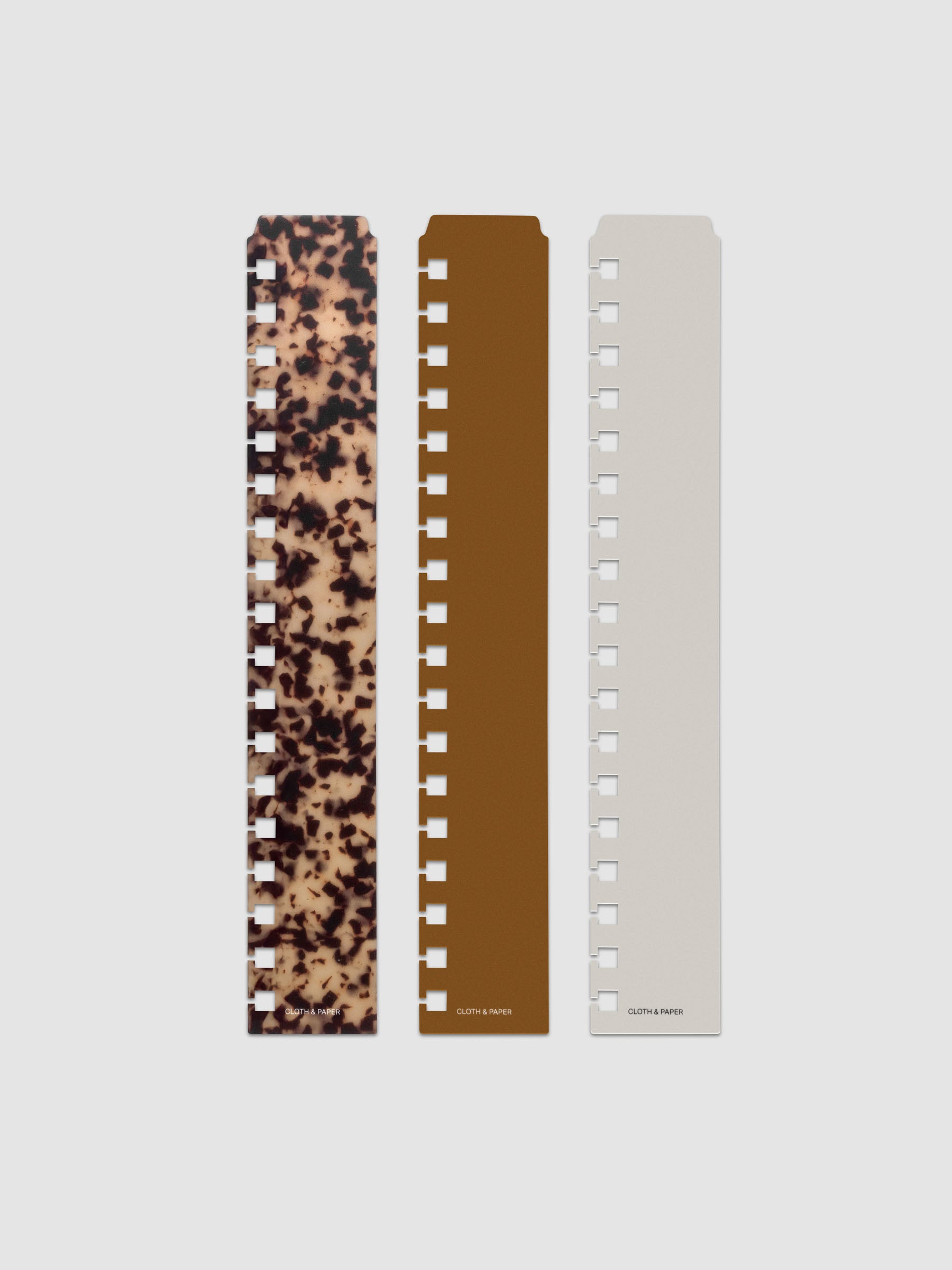 Narrow Page Marker Set Vol. 2, a set of 3 page markers for planners and notebooks shown in size HP Classic Spiral. Includes one tortoiseshell pattern, one solid brown, and one solid grey page marker.