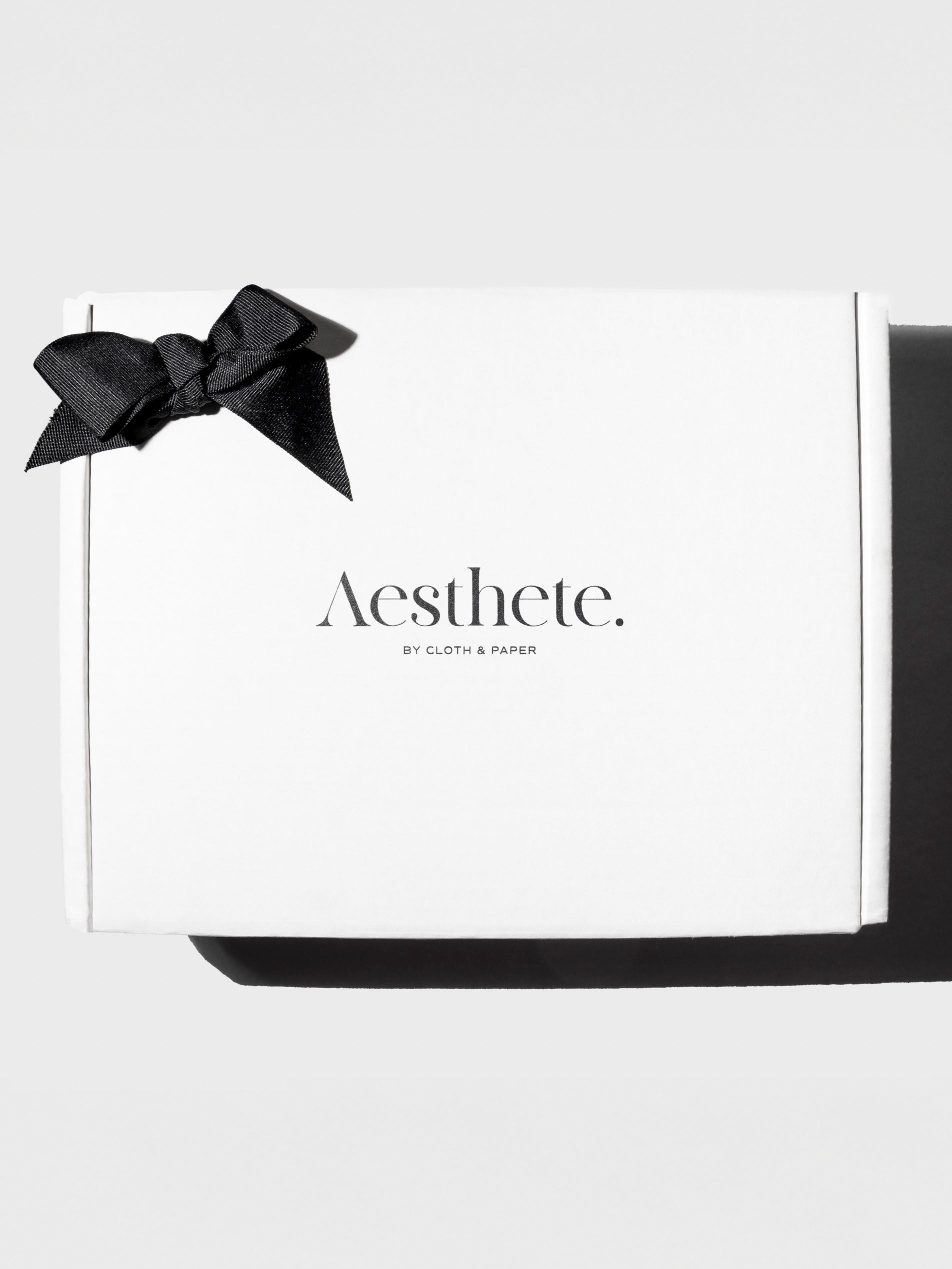 Aesthete Mystery Box, Cloth and Paper. Aesthete box adorned with a black bow displayed on a neutral background.
