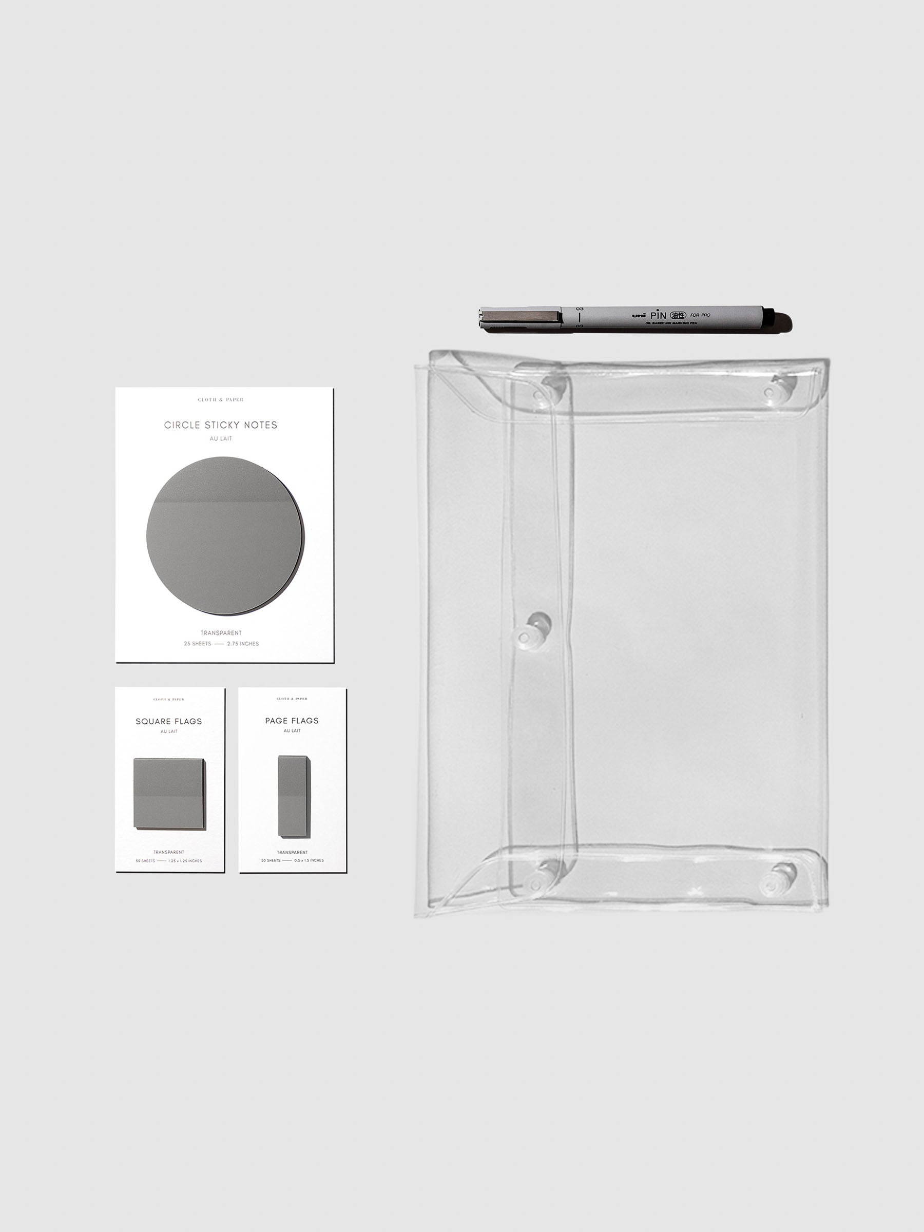 Matching set of circle sticky notes, page flags, and square page flags positioned next to a Uni Pin Marking Pen and Essentials Clear pouch. Sticky note color is Au Lait.