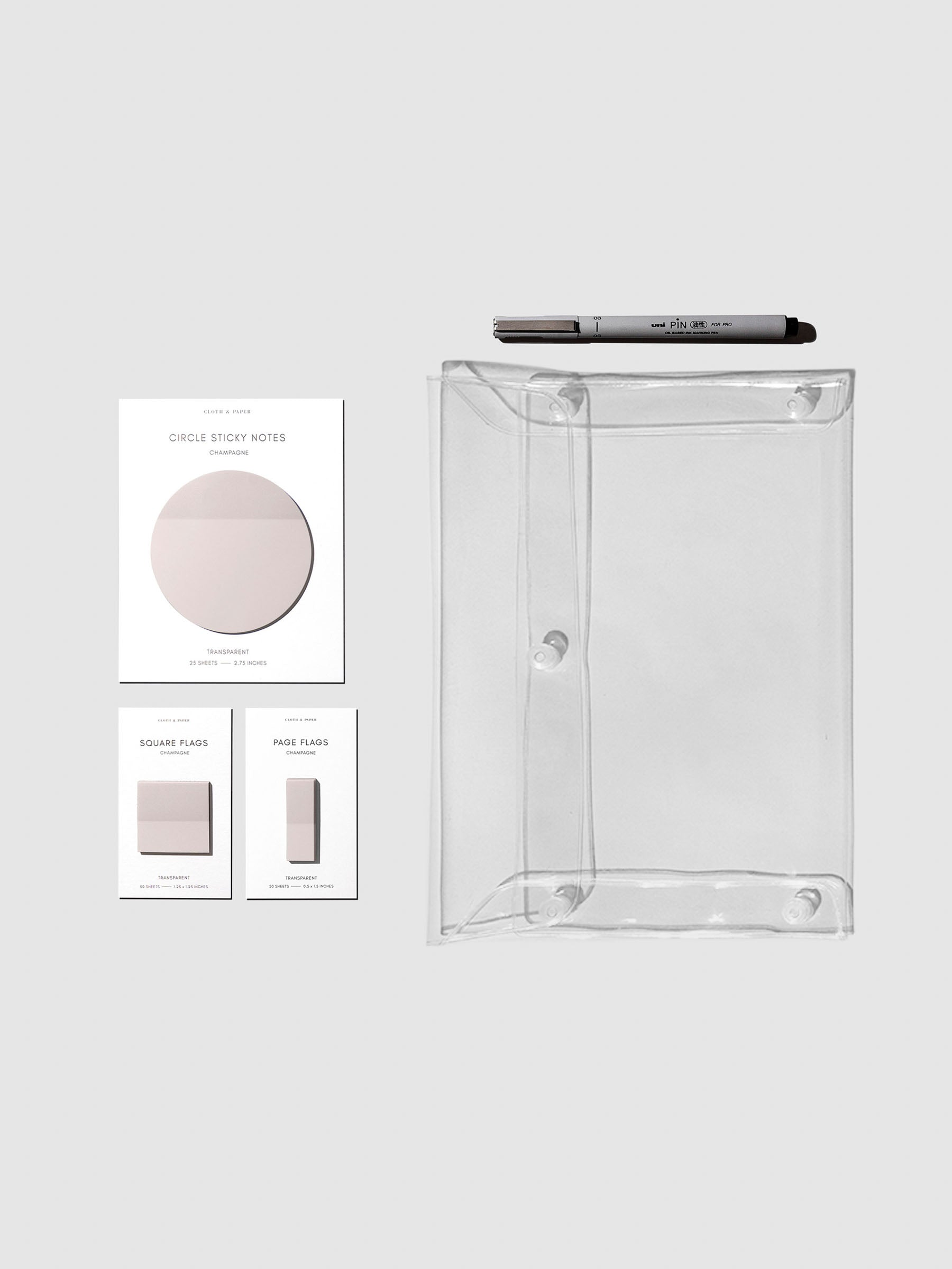 Matching set of circle sticky notes, page flags, and square page flags positioned next to a Uni Pin Marking Pen and Essentials Clear pouch. Sticky note color is Champagne.