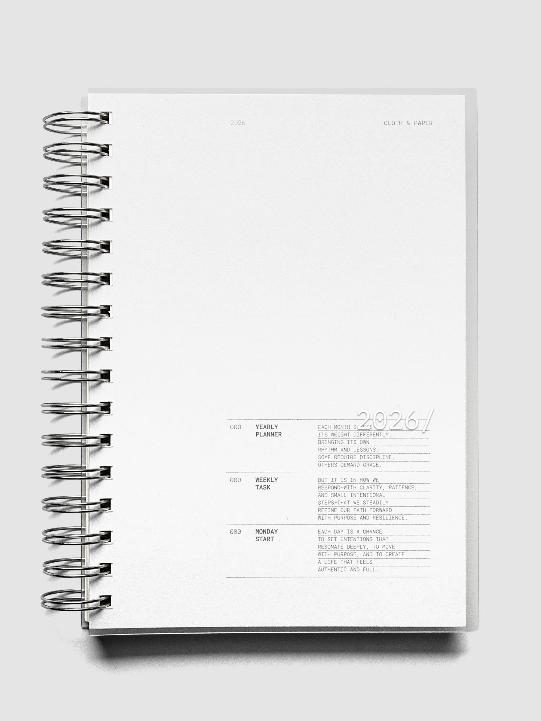 Silver spiral bound notebook with a clear cover featuring white 2026 text on a neutral background.