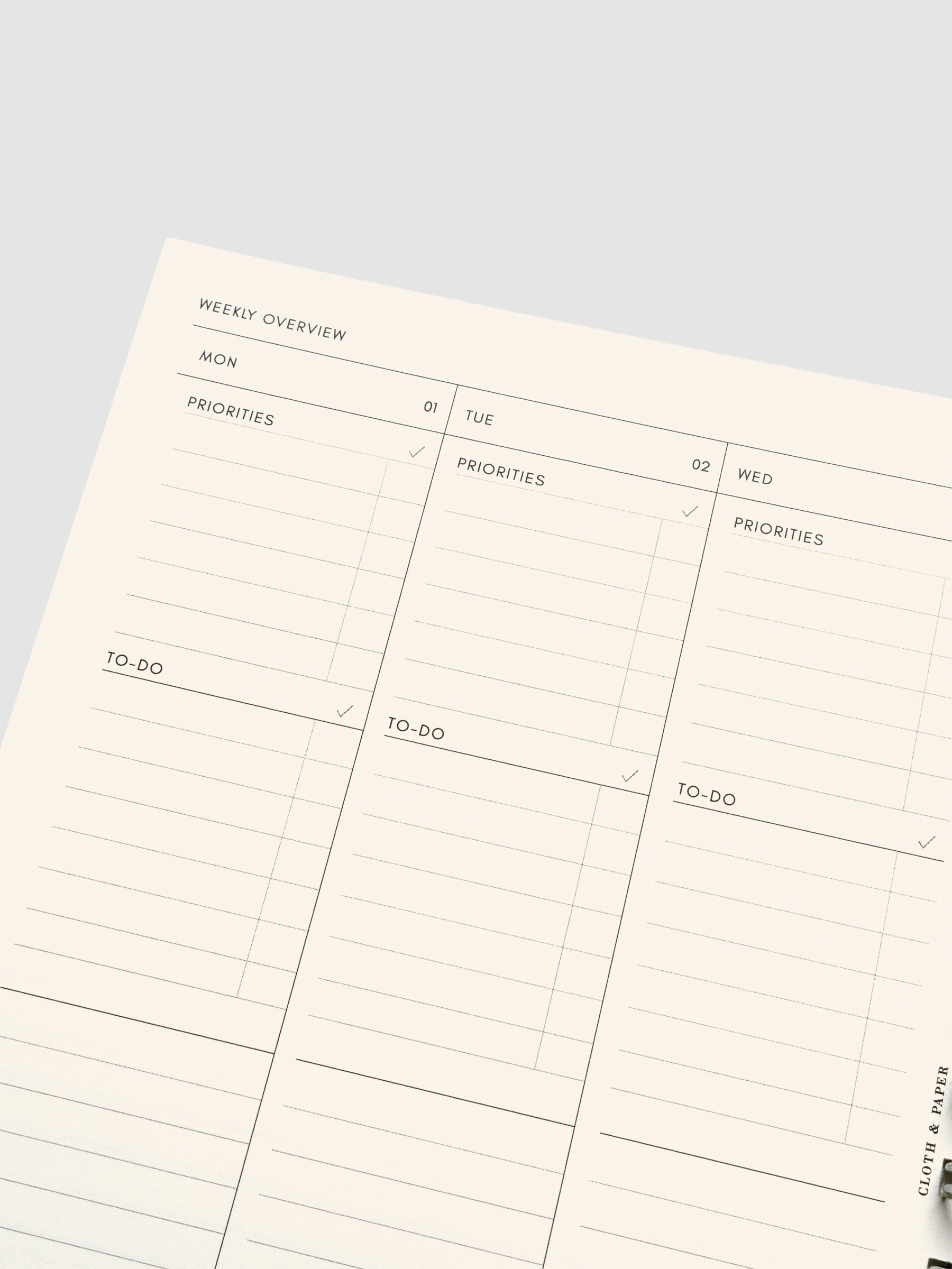 Close up of a weekly task layout page on cream paper showing daily sections for priorities and to-dos.