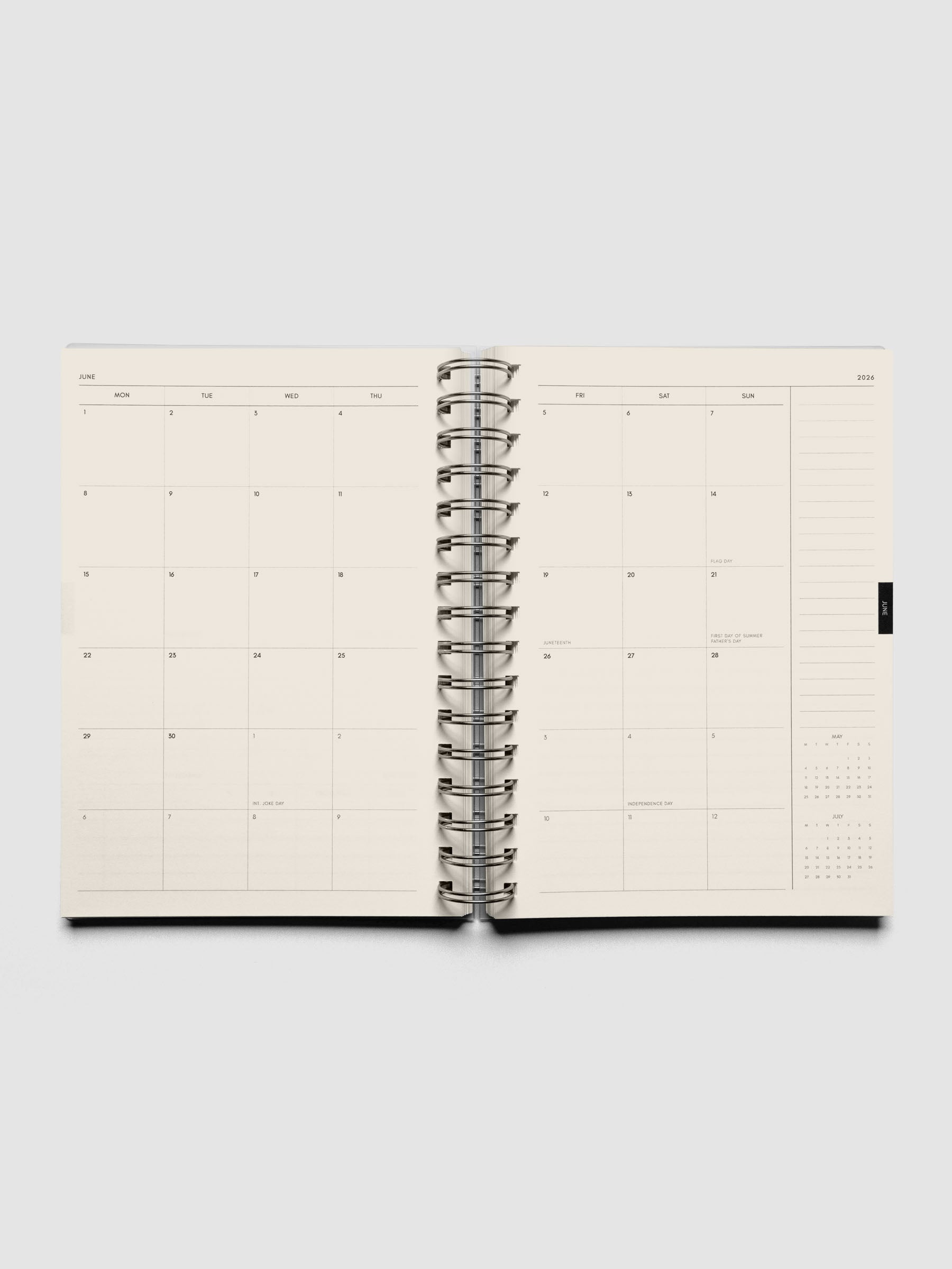 Open spiral notebook showing a monthly calendar layout with a lined notes section on the right hand side above a month-at-a-glance view.