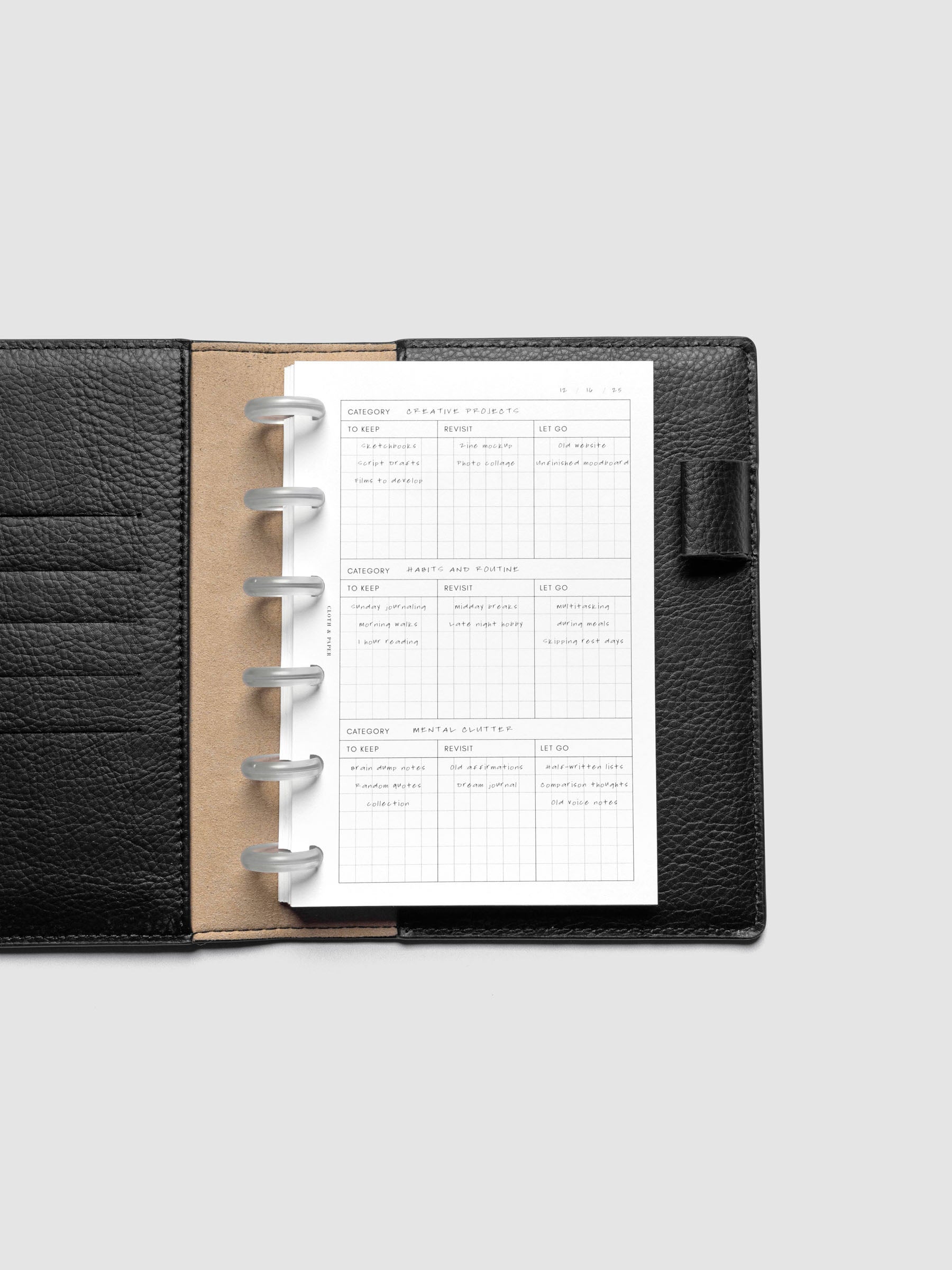 Declutter Planner Inserts with handwritten notes in size CP Petite shown discbound in a black leather folio.