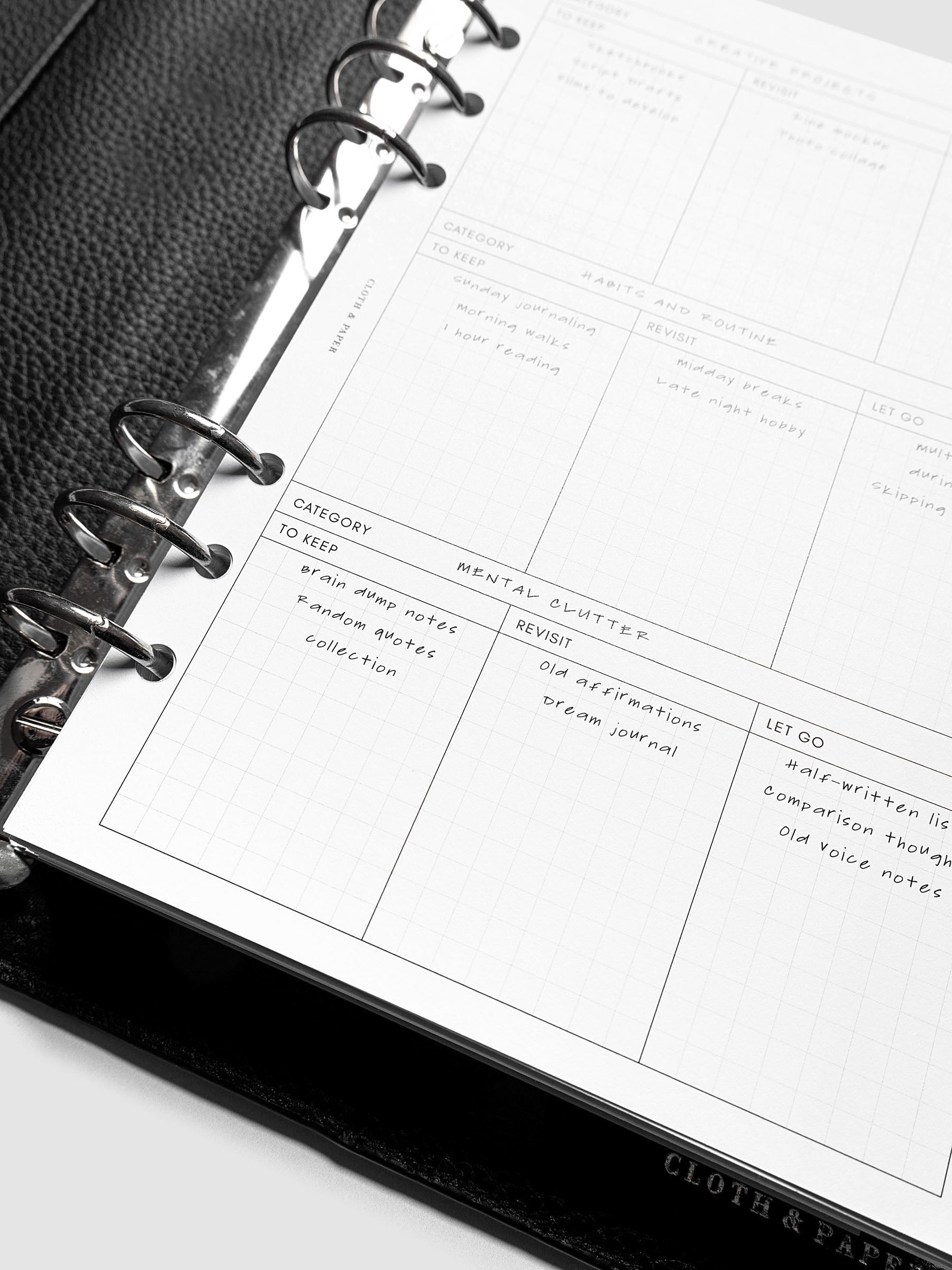Close up of Declutter Planner Inserts in size A5 shown ring bound in a black leather agenda with handwritten notes.