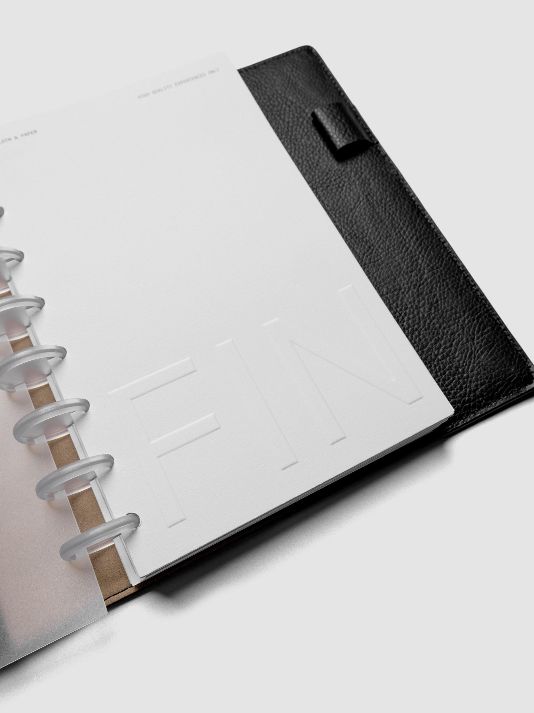 Close up of Closure Planner Dashboard + Cover Set in size Half Letter shown discbound in a black leather folio cover displaying FIN text on dashboard.