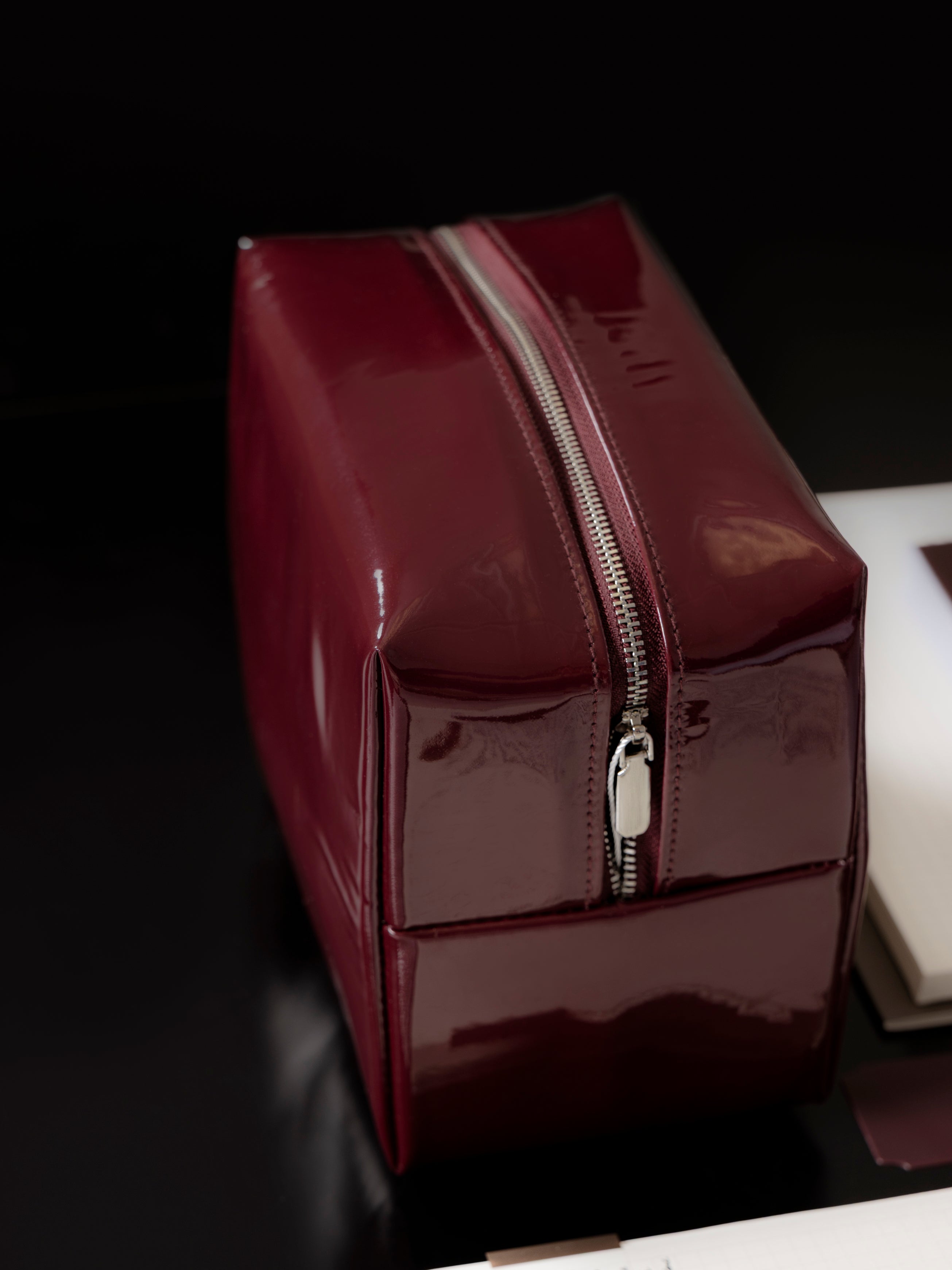 Deep red Lacquered Pouch shown from the side against a black background.