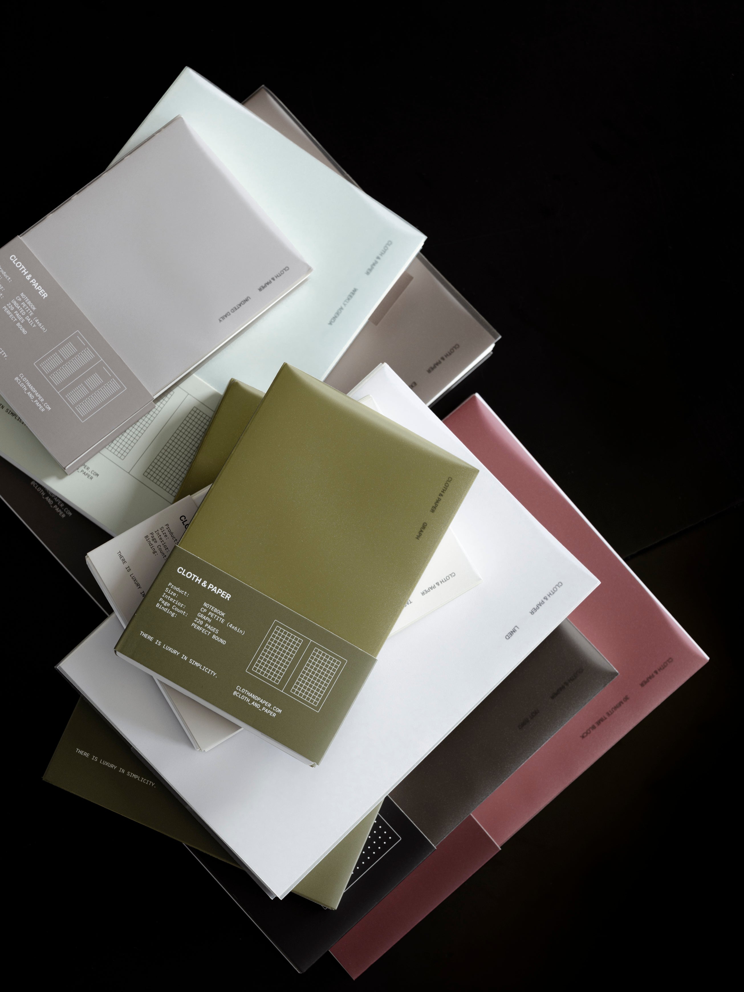 Cloth & Paper Perfect Bound Notebooks stacked on a dark background.