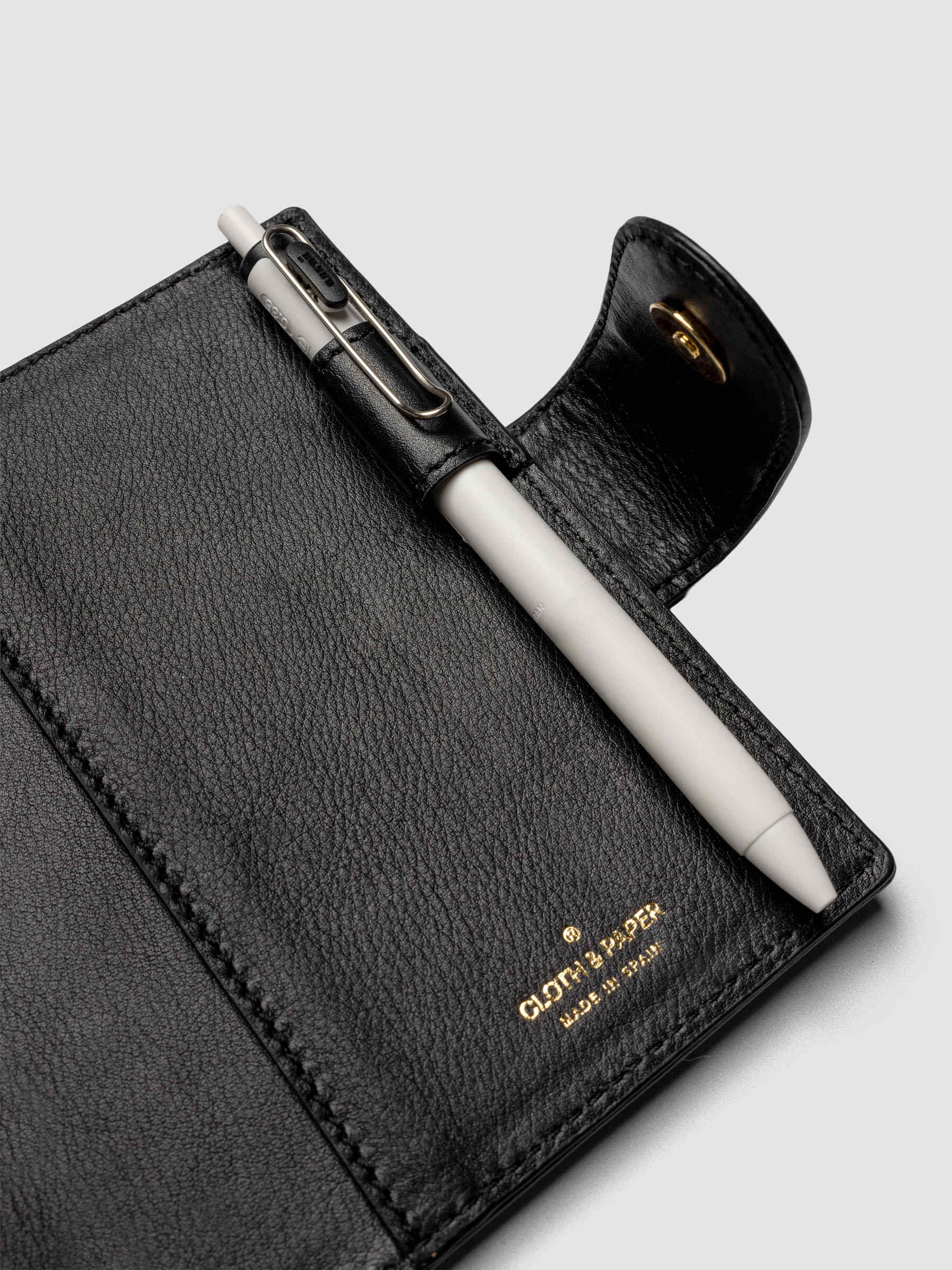 Heirloom Ring Cover Genuine Leather Pocket 6-Ring Punch in black, detail view of interior pen loop, large pocket, and closure with pen in pen loop