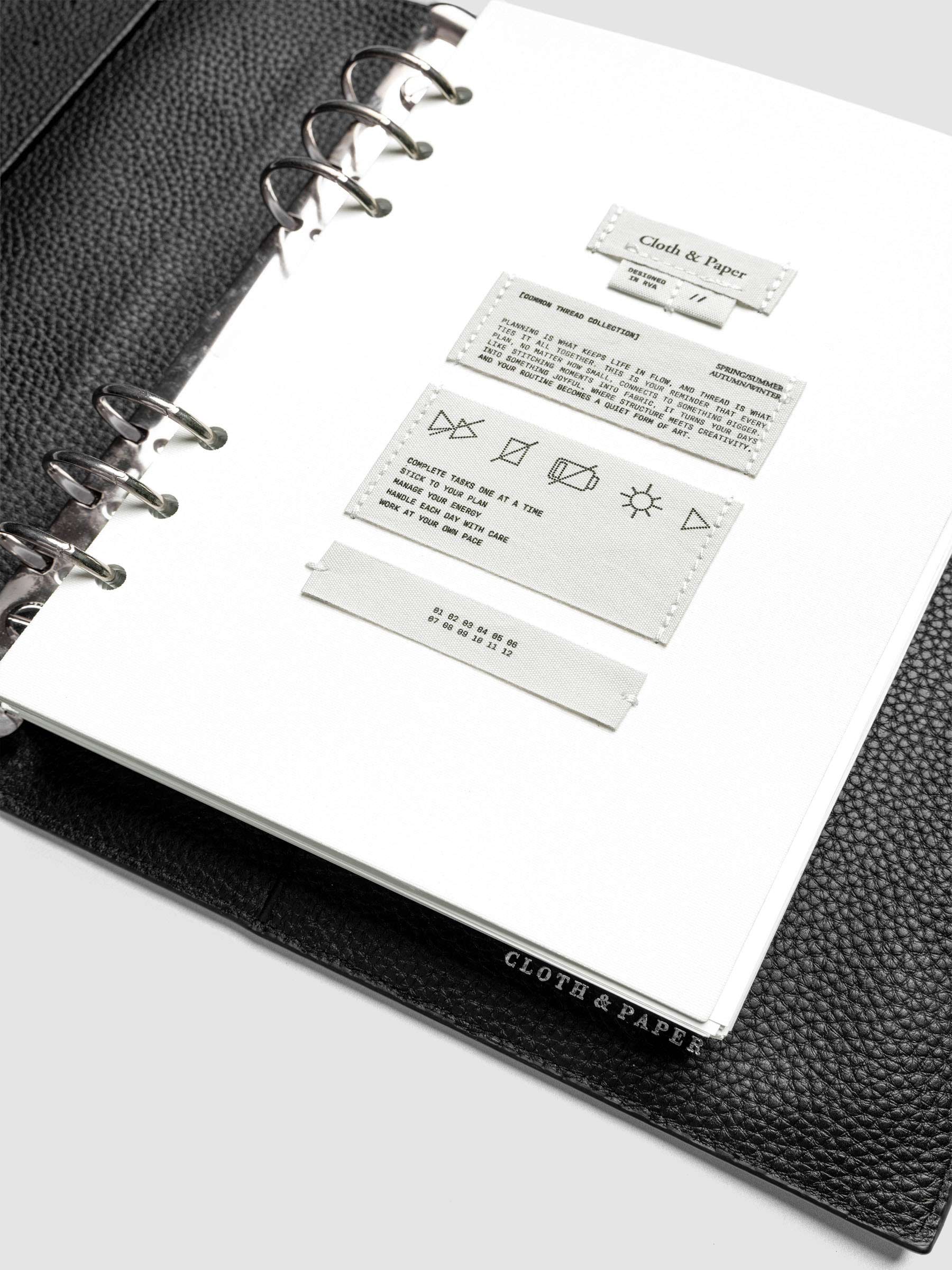 Sewn Tags Planner Dashboard pre-punched for 6-ring planners in size A5 shown in a black leather agenda.